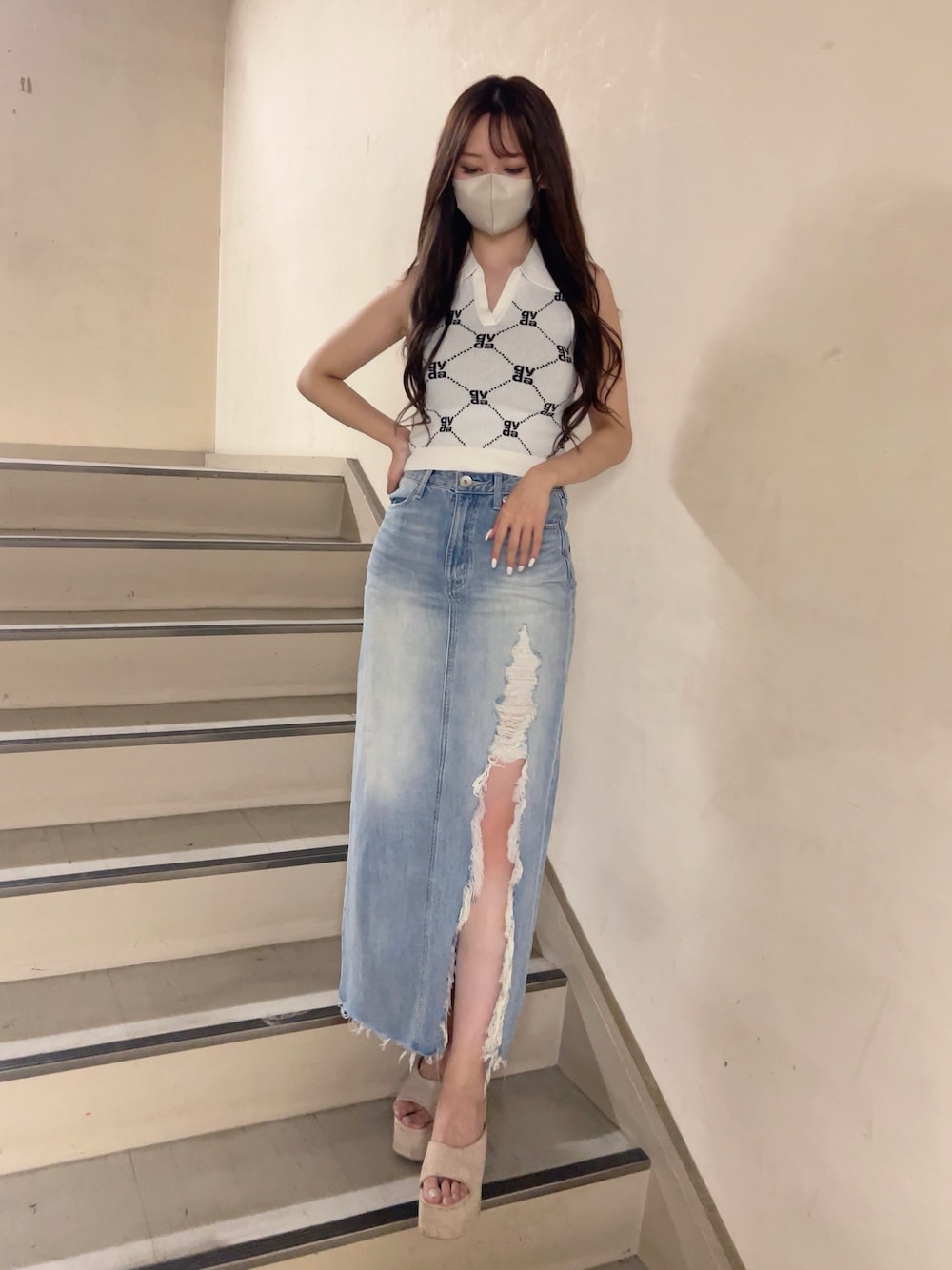 ホワイト系のニット/セーター、ブルー系のデニムスカート、ホワイト系のサンダルを着用したレディースの春コーディネートの1枚目の写真