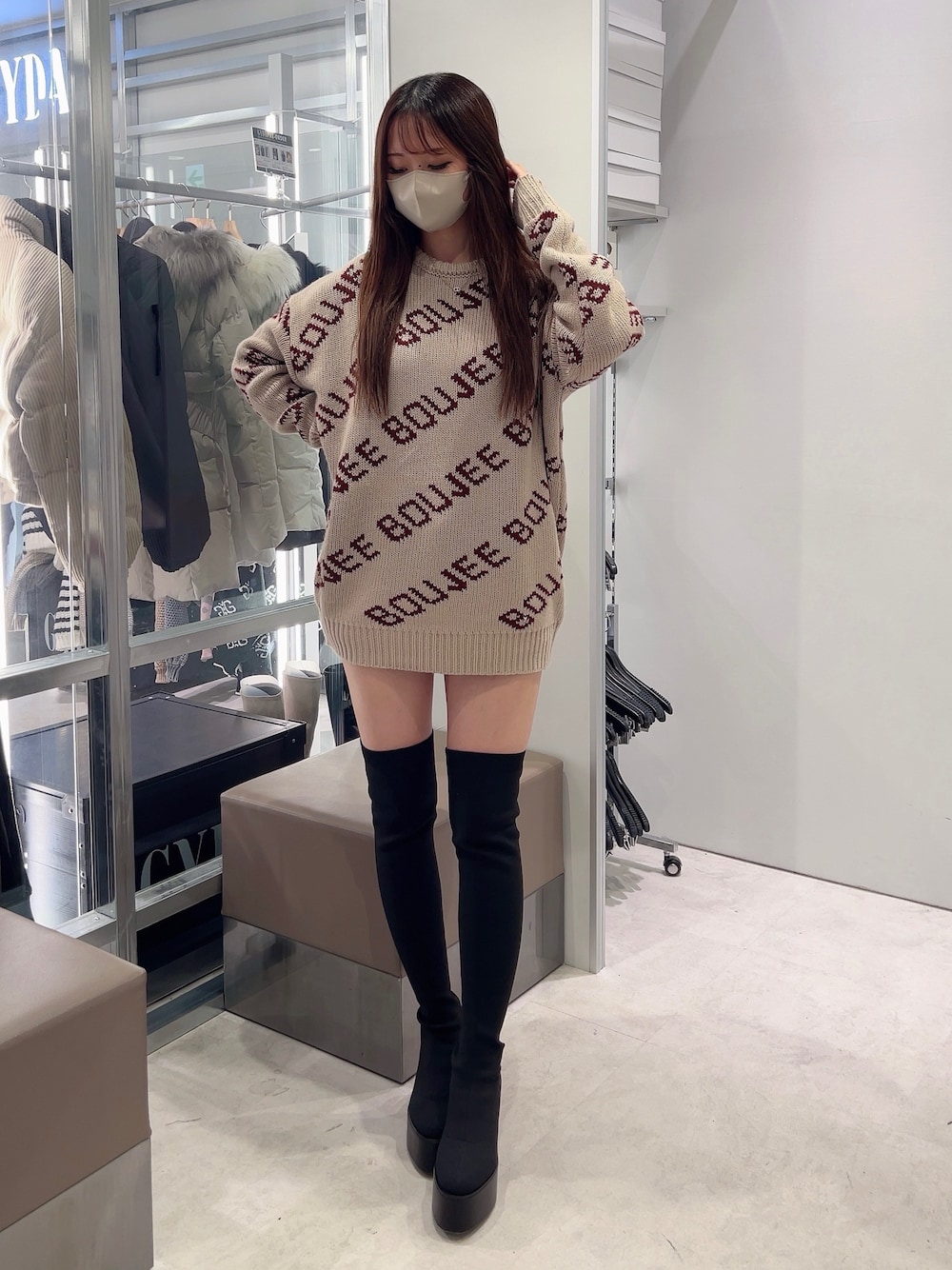 ベージュ系のニット/セーター、ブラック系のスカート、ブラック系のブーツを着用したレディースの秋コーディネートの1枚目の写真