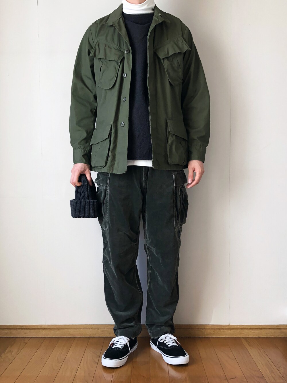 グリーン系のミリタリージャケット、グレー系のベスト、ホワイト系のTシャツ/カットソーを着用したメンズの冬コーディネートの1枚目の写真