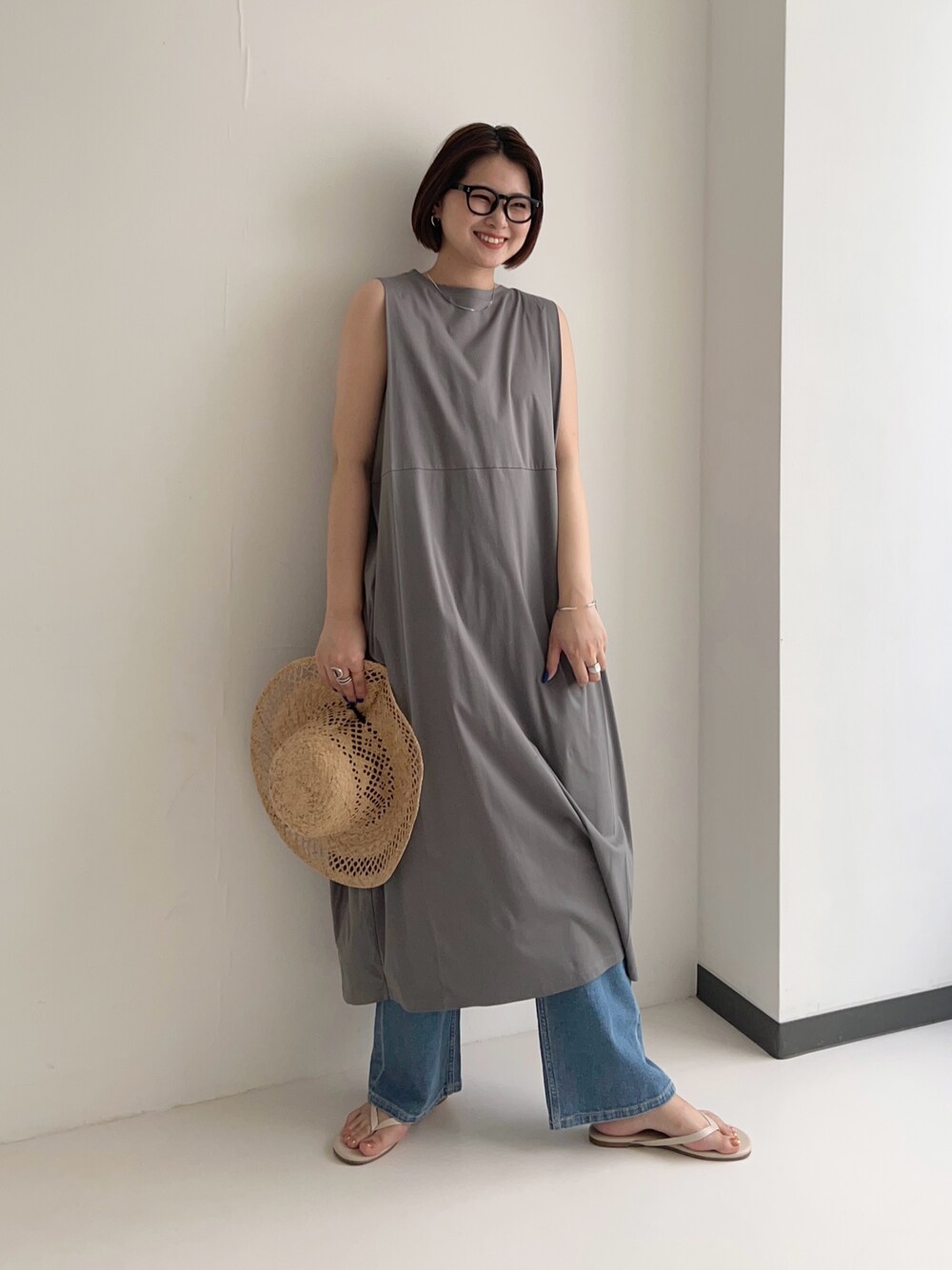 グレー系のワンピース、ブルー系のデニムパンツ、シルバー系のネックレスを着用したレディースの夏コーディネートの1枚目の写真
