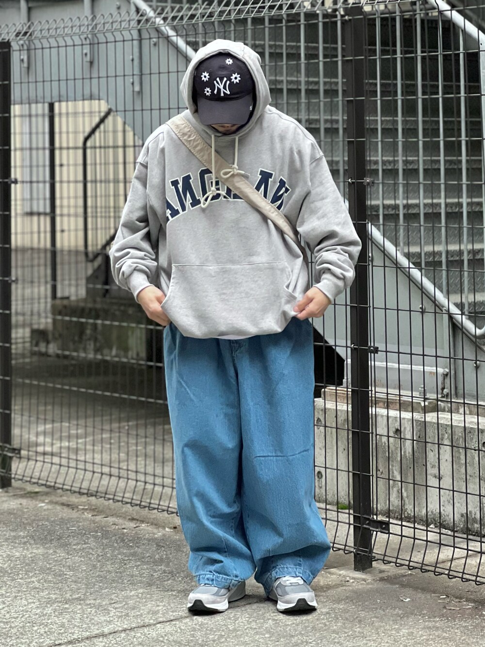 グレー系のパーカー、グレー系のスニーカー、ブルー系のデニムパンツを着用したメンズの春コーディネートの1枚目の写真