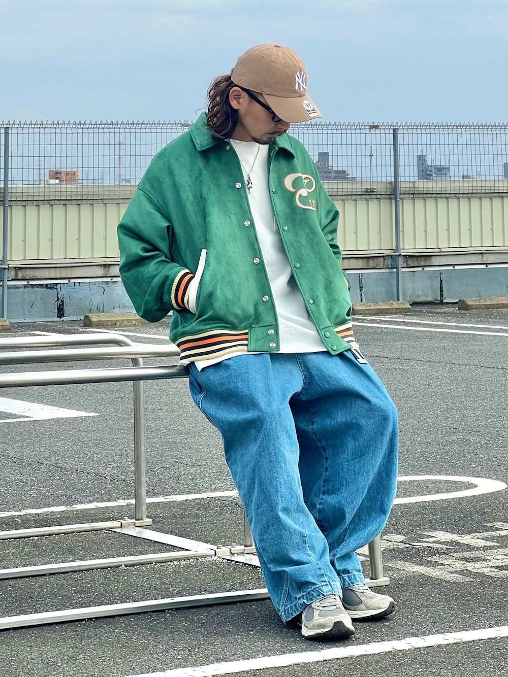 グリーン系のスタジャン、ブルー系のデニムパンツ、ベージュ系のキャップを着用したメンズの春コーディネートの1枚目の写真