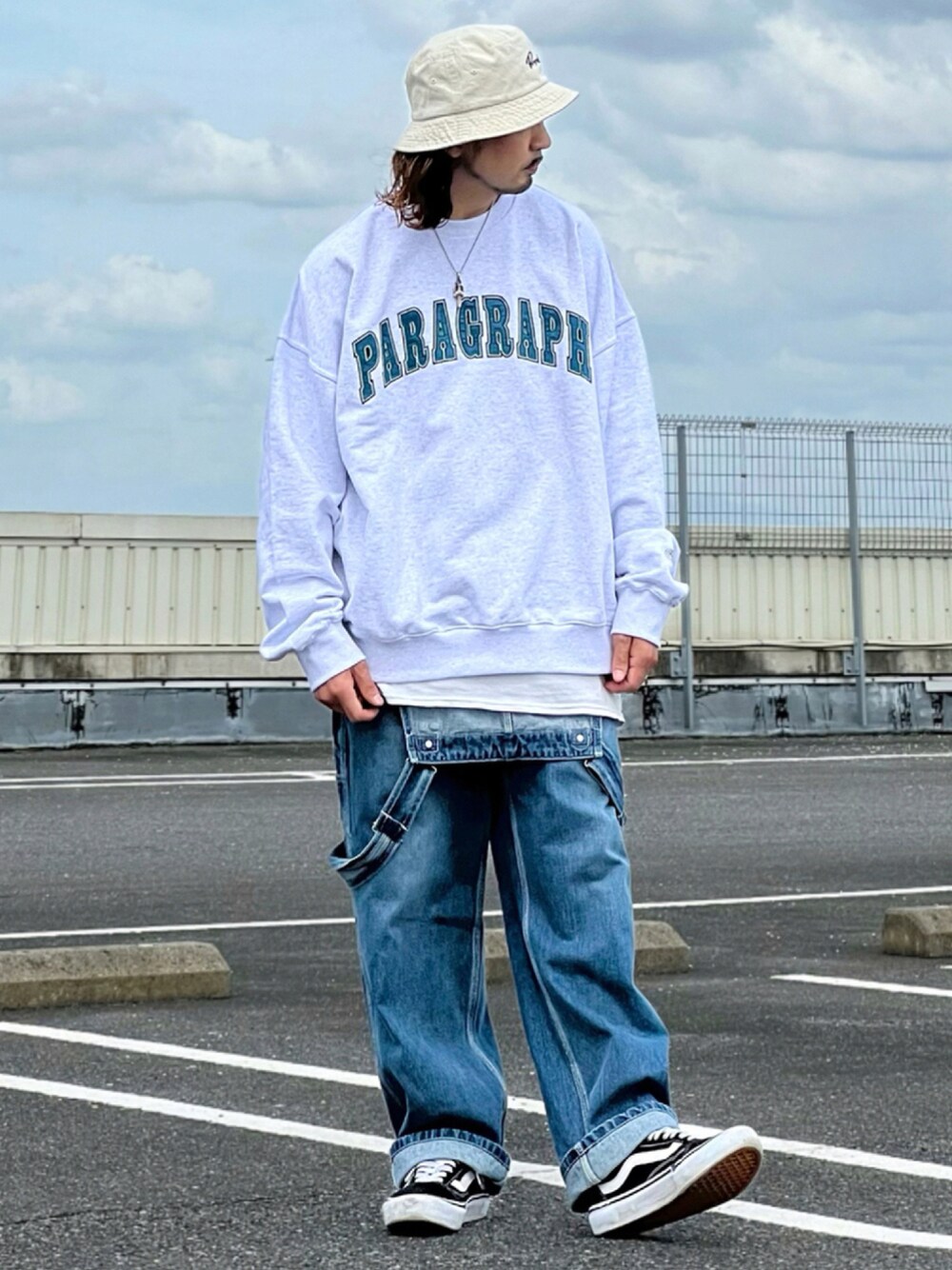 ホワイト系のスウェット、ブルー系のサロペット/オーバーオール、ブラック系のスニーカーを着用したメンズの秋コーディネートの1枚目の写真