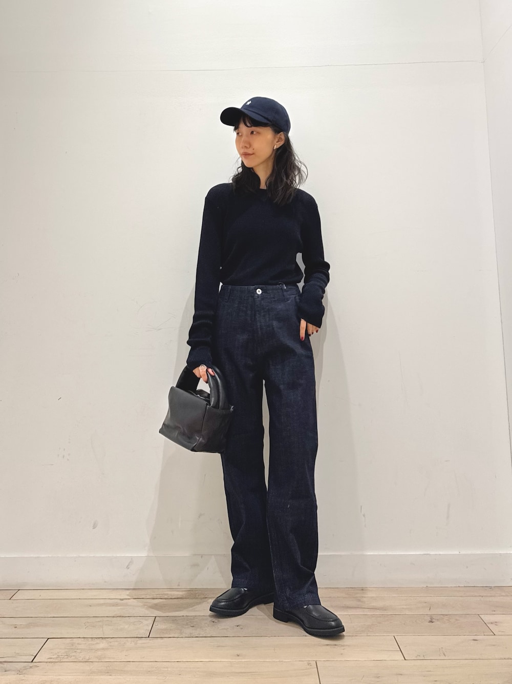 ブルー系のニット/セーター、ブルー系のデニムパンツ、ブラック系のハンドバッグを着用したレディースの秋コーディネートの1枚目の写真