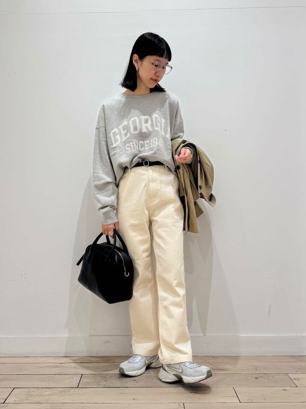 ブラック系のボストンバッグ、シルバー系のスニーカー、ベージュ系のデニムパンツを着用したレディースの冬コーディネートの1枚目の写真