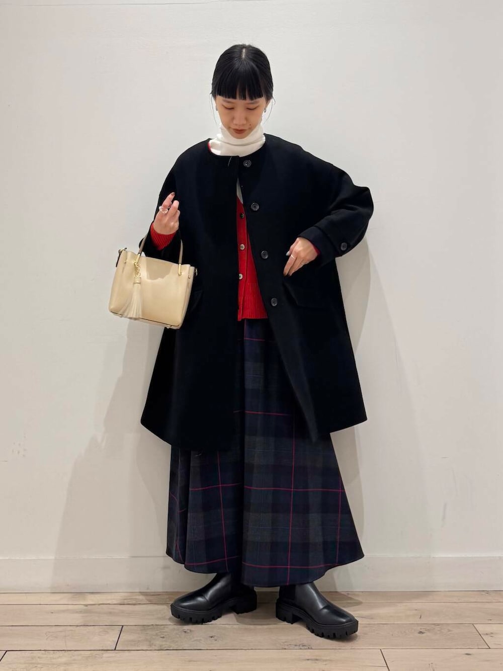 ホワイト系のトートバッグ、ブラック系のノーカラーコート、ブラック系のブーツを着用したレディースの冬コーディネートの1枚目の写真