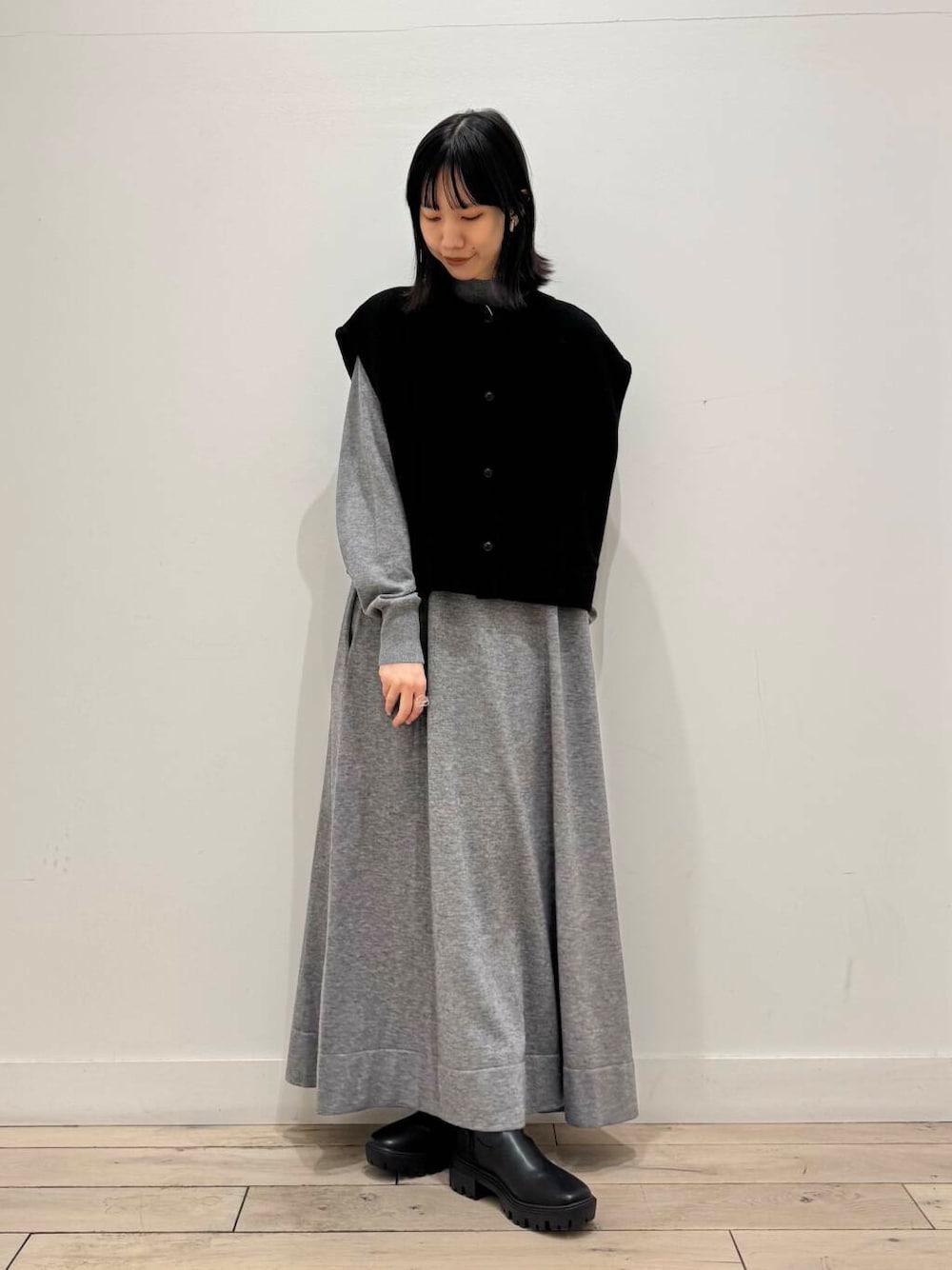 ブラック系のブーツ、グレー系のワンピース、ブラック系のベストを着用したレディースの冬コーディネートの1枚目の写真