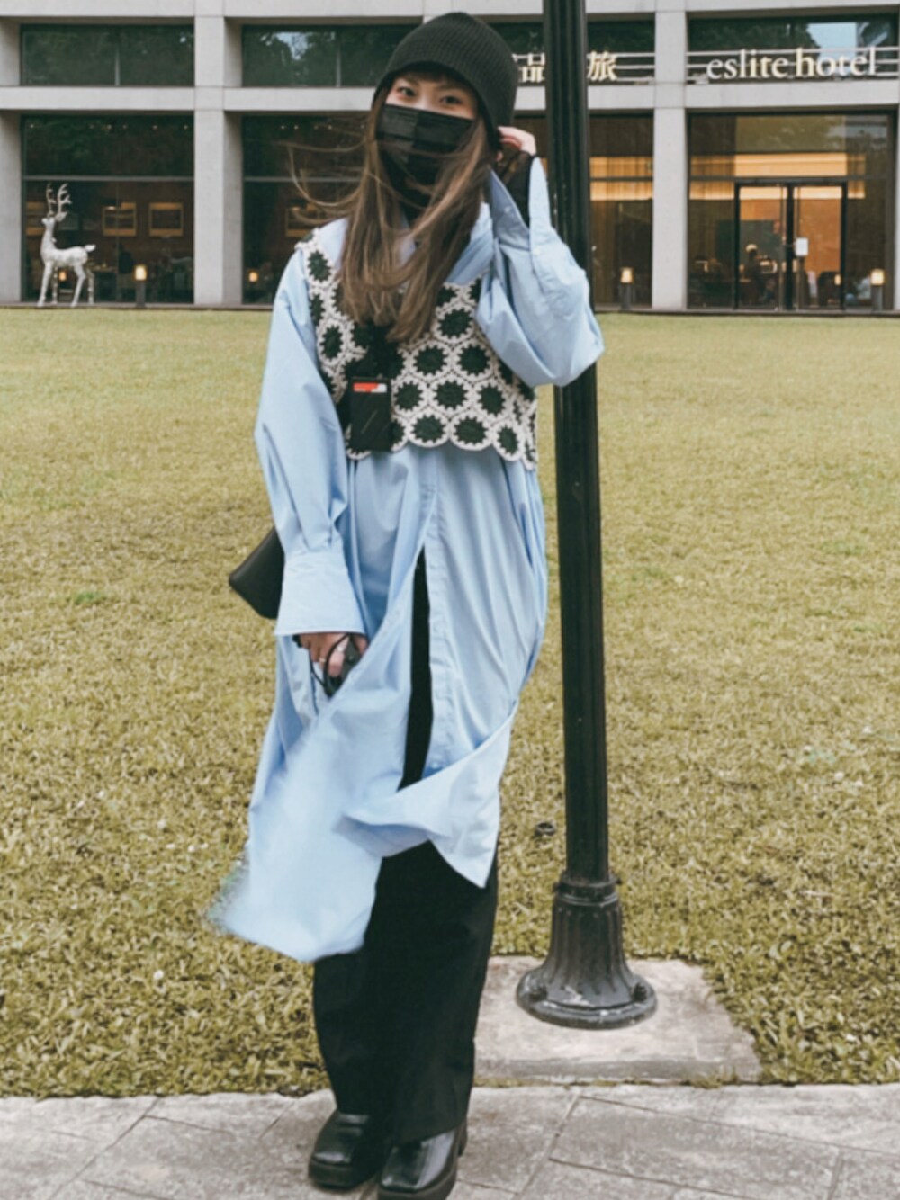 グリーン系のベスト、ホワイト系のシャツワンピース、ブラック系のパンツを着用したレディースの春コーディネートの1枚目の写真