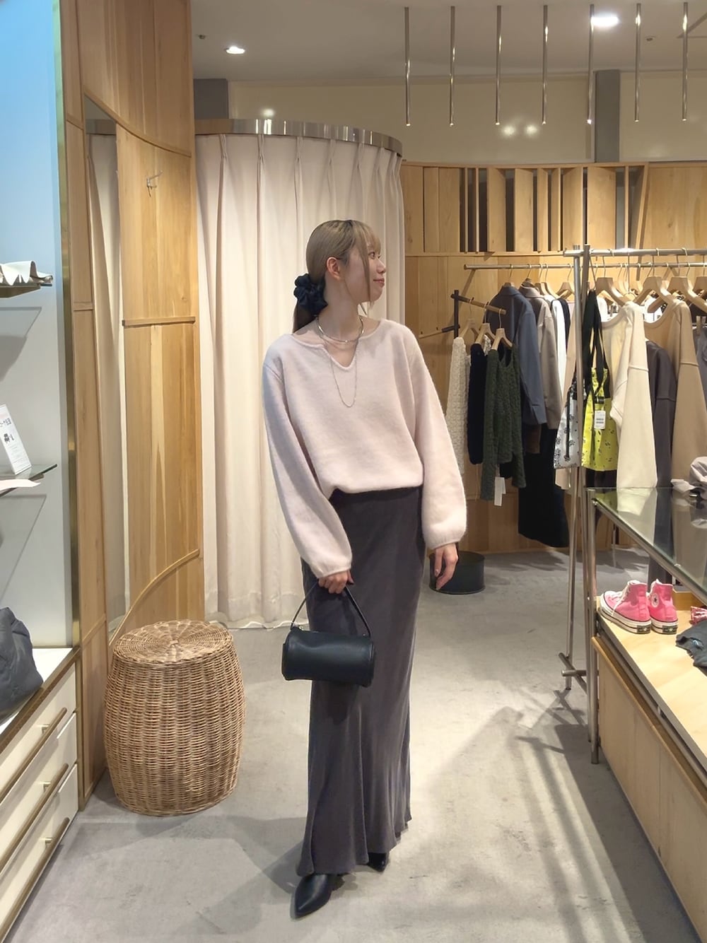 ピンク系のニット/セーター、グレー系のスカート、ブラック系のブーツを着用したレディースの秋コーディネートの1枚目の写真