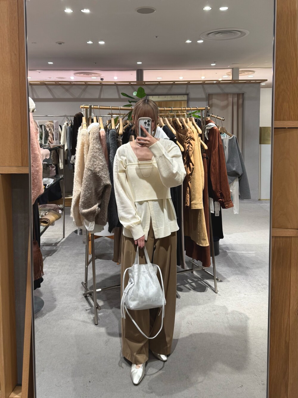 シルバー系のトートバッグ、ベージュ系のスラックス、ゴールド系のパンプスを着用したレディースの秋コーディネートの1枚目の写真