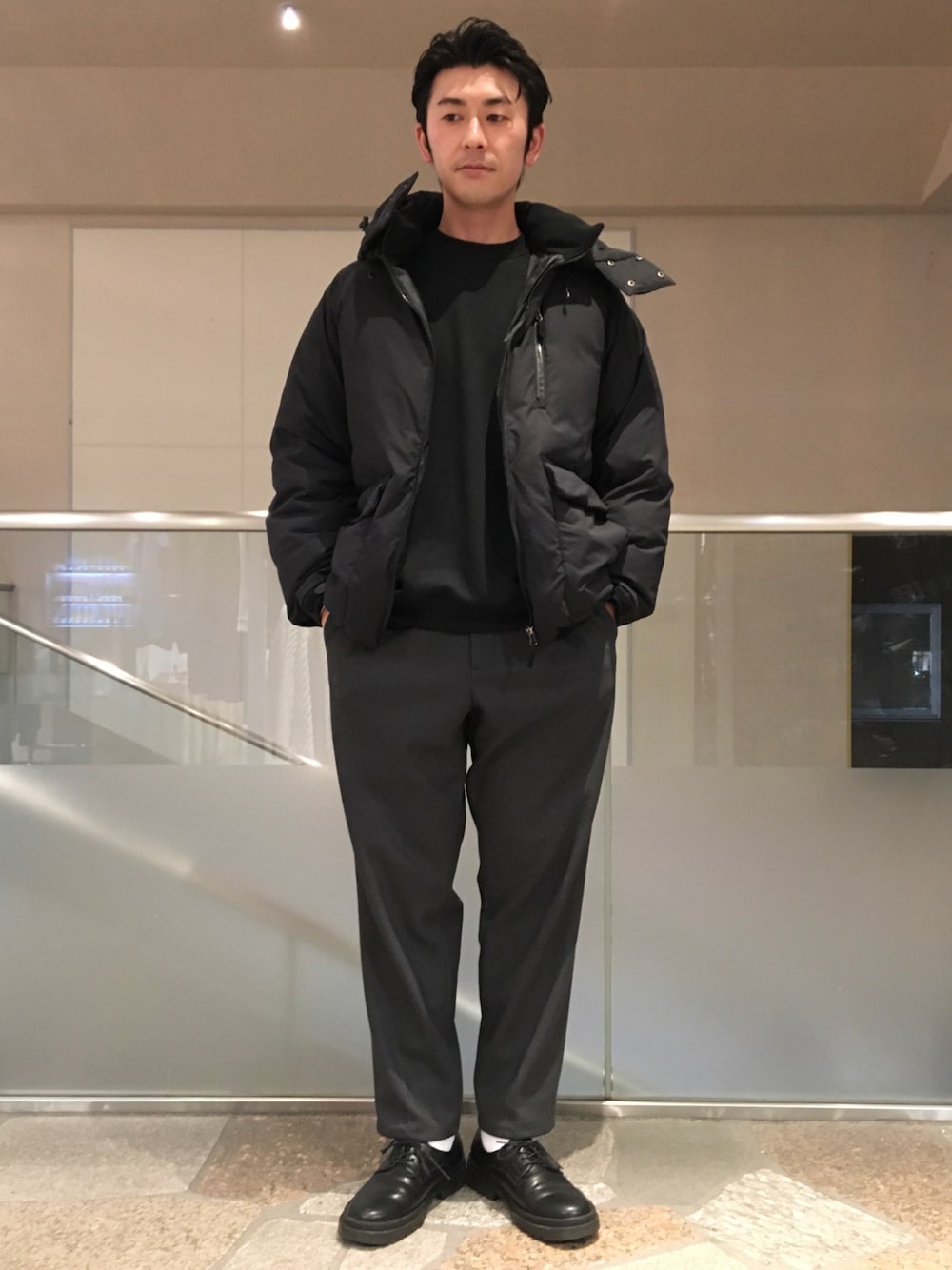 ブラック系のスウェット、ブラック系のダウンジャケット/コート、グレー系のスラックスを着用したメンズの冬コーディネートの1枚目の写真