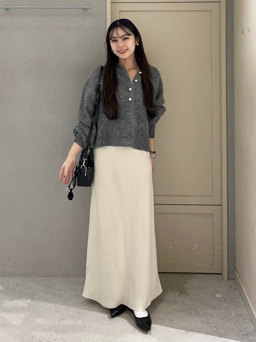 ホワイト系のスカート、ブラック系のパンプス、ブラック系のボストンバッグを着用したレディースの秋コーディネートの1枚目の写真