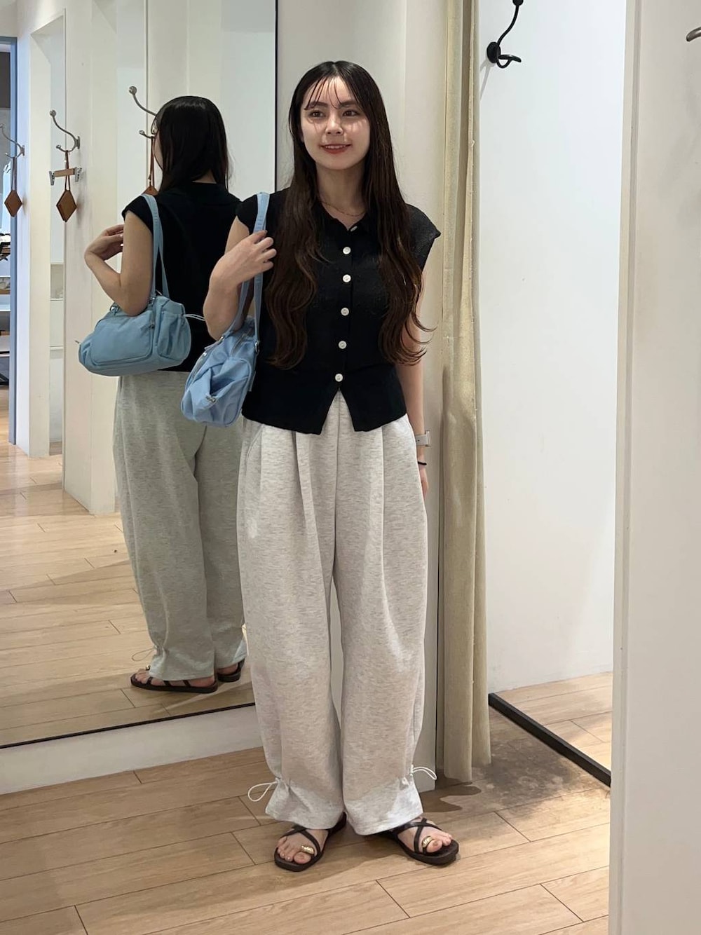 グレー系のスウェットパンツ、ブラック系のベスト、ブラウン系のサンダルを着用したレディースの夏コーディネートの1枚目の写真