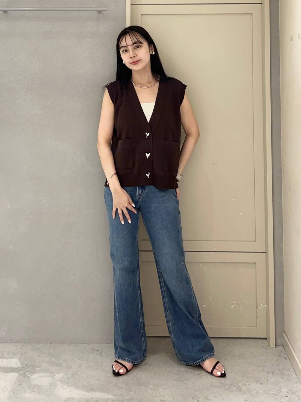 ホワイト系のキャミソール、ブラック系のサンダル、ブルー系のデニムパンツを着用したレディースの夏コーディネートの1枚目の写真