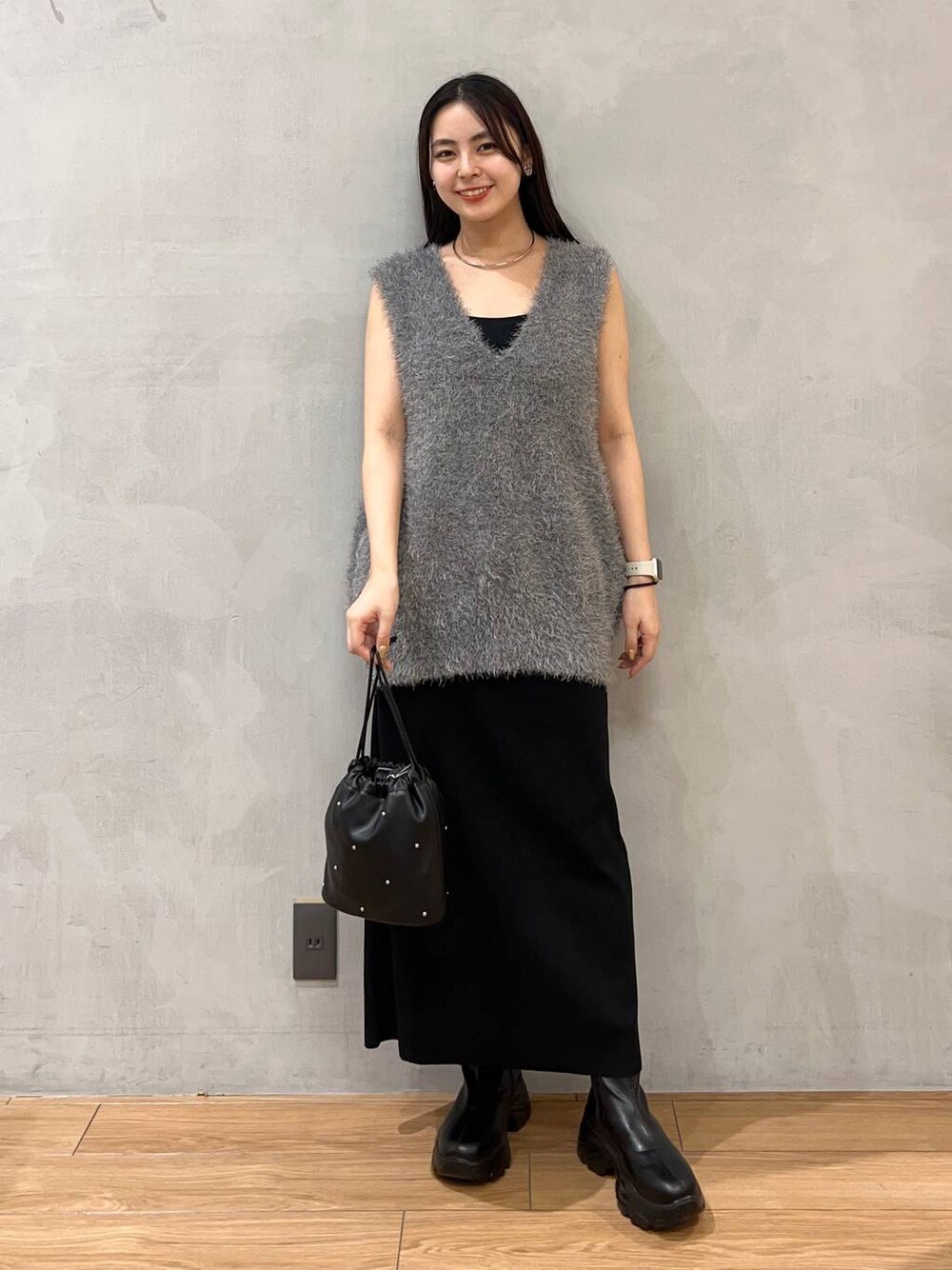 ブラック系のスカート、ブラック系のショルダーバッグ、グレー系のベストを着用したレディースの夏コーディネートの1枚目の写真