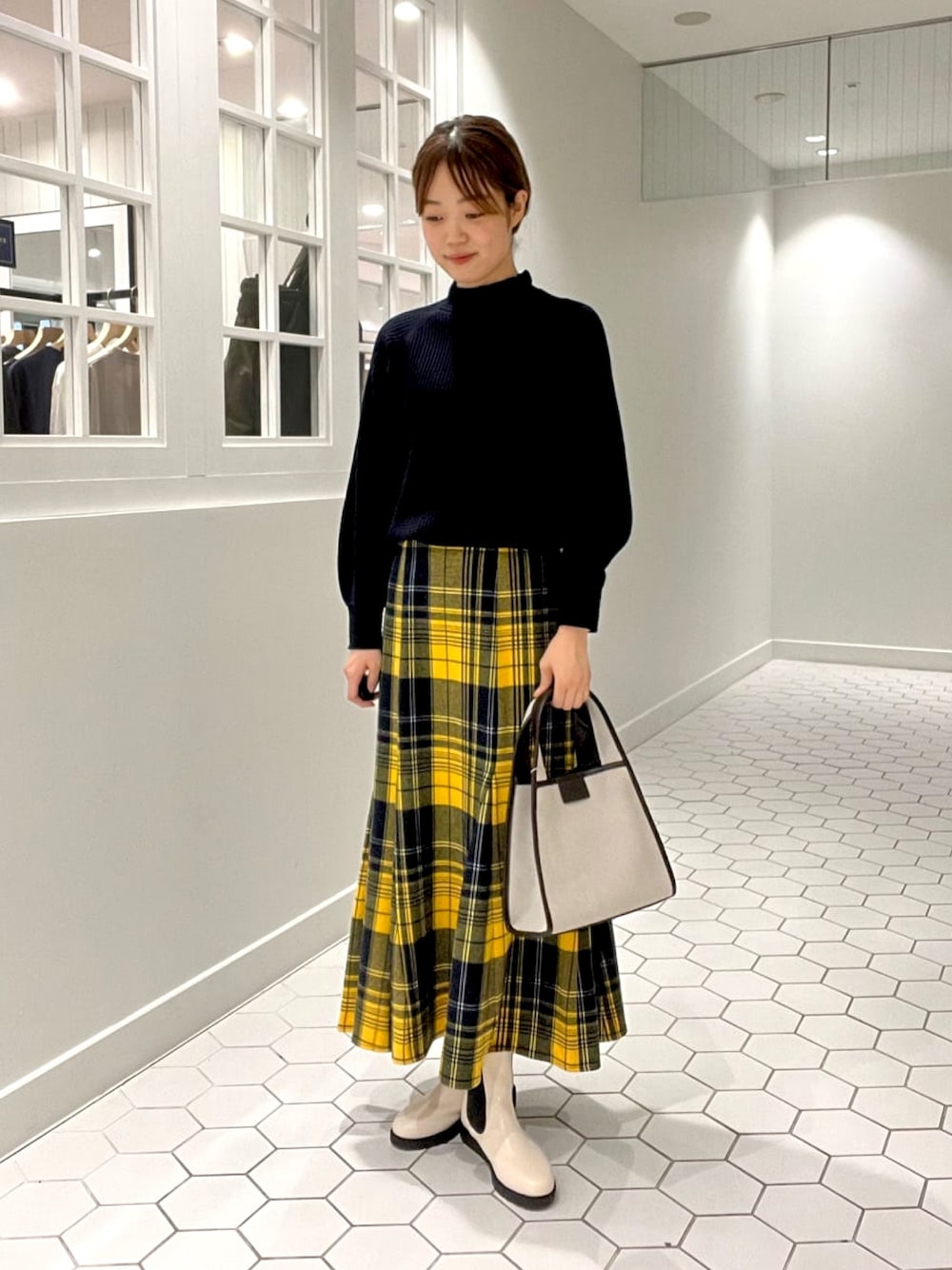 ブルー系のニット/セーター、イエロー系のスカート、ブラウン系のトートバッグを着用したレディースの秋コーディネートの1枚目の写真