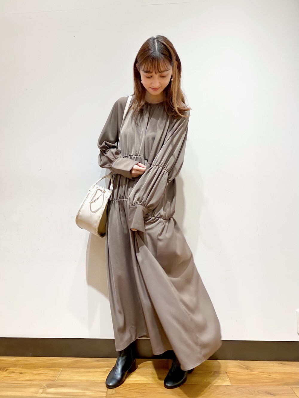 ブラウン系のドレス、ホワイト系のショルダーバッグ、ブラック系のブーツを着用したレディースの秋コーディネートの1枚目の写真