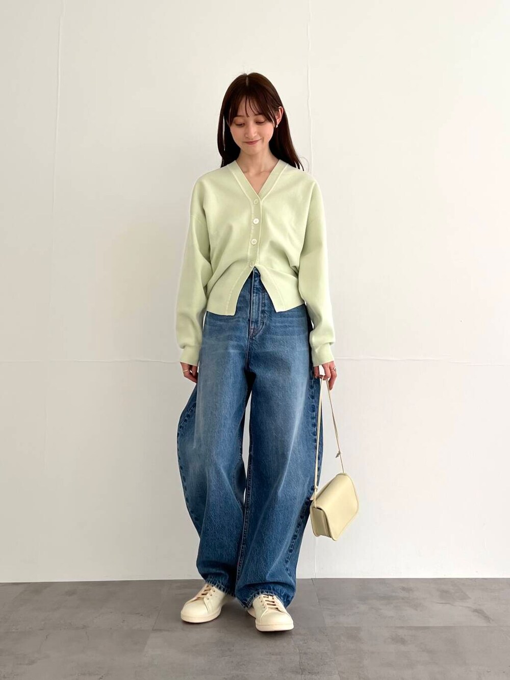 ブルー系のデニムパンツ、ホワイト系のショルダーバッグ、ホワイト系のスニーカーを着用したレディースの冬コーディネートの1枚目の写真