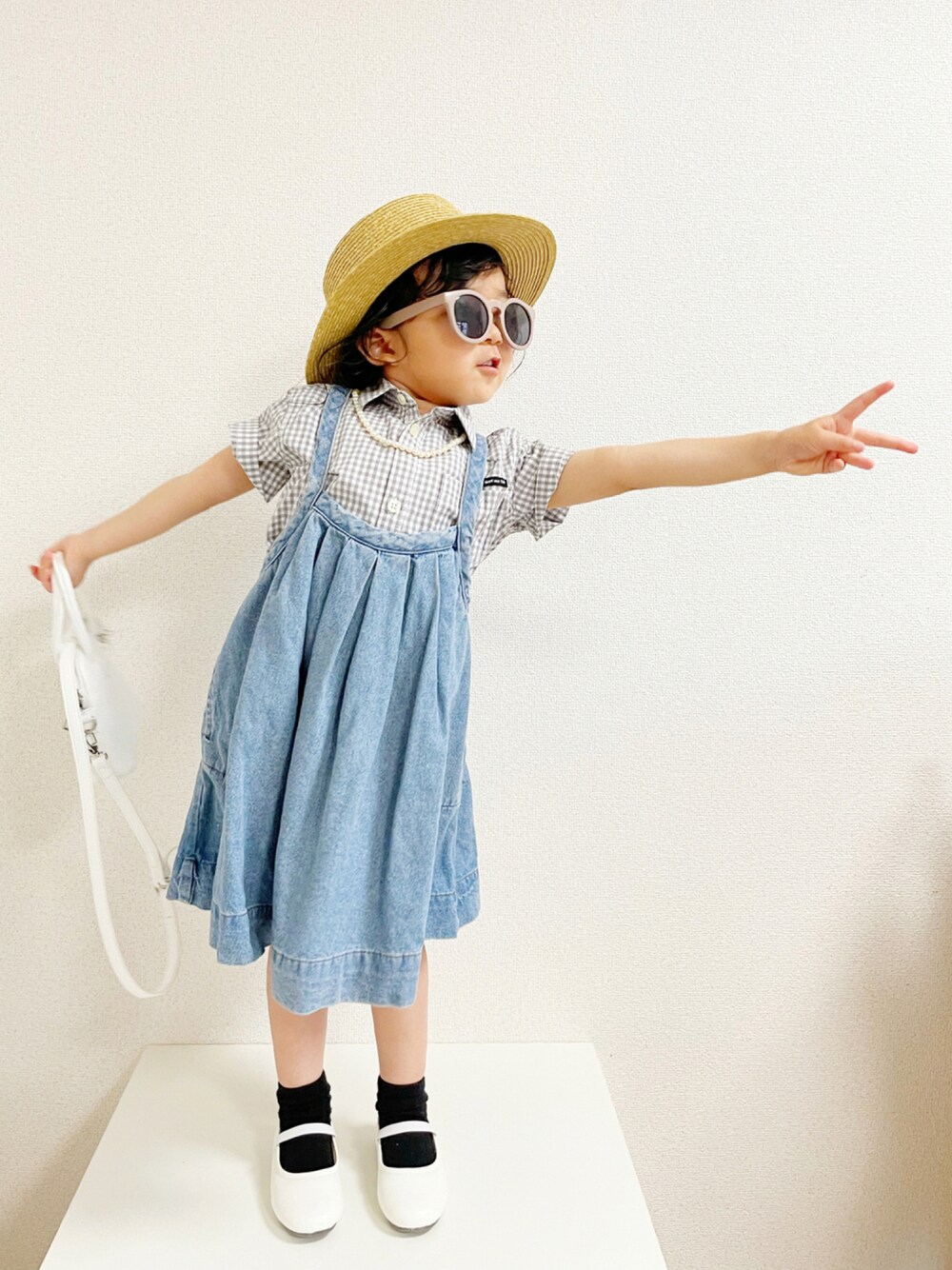 グレー系のシャツ/ブラウス、ブルー系のジャンパースカート、ホワイト系のトートバッグを着用したキッズの夏コーディネートの1枚目の写真