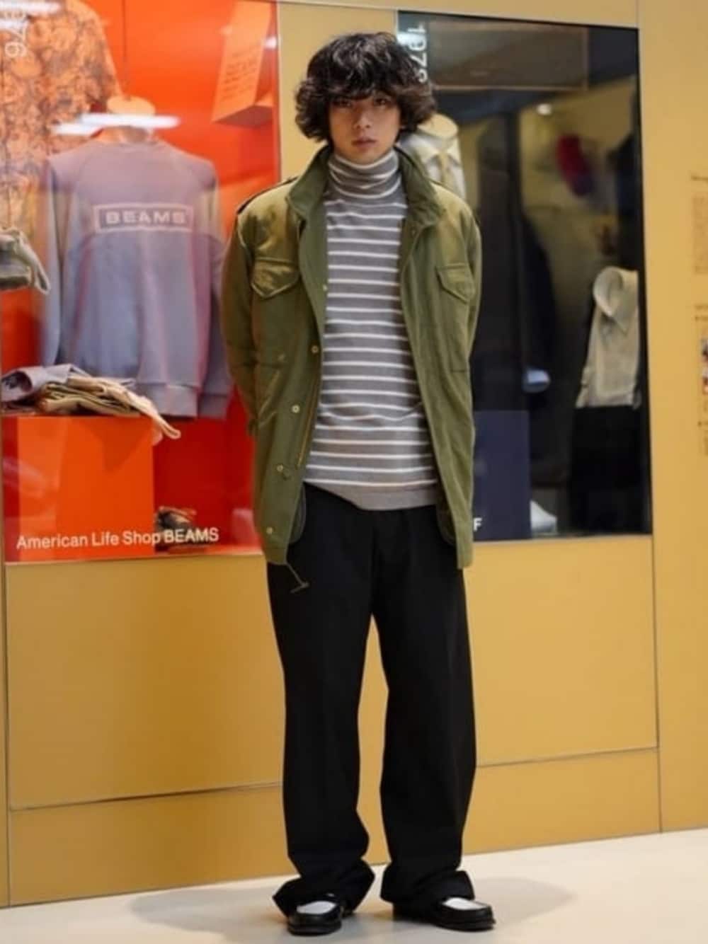 グリーン系のブルゾン、グレー系のニット/セーター、ブラック系のスラックスを着用したメンズの秋コーディネートの1枚目の写真