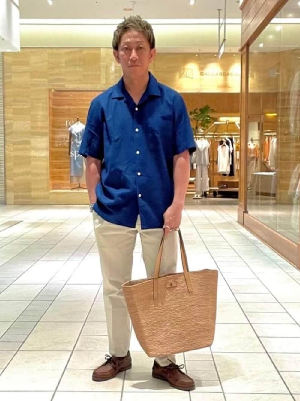グリーン系のトートバッグ、ブラウン系のドレスシューズを着用したメンズの春コーディネートの1枚目の写真