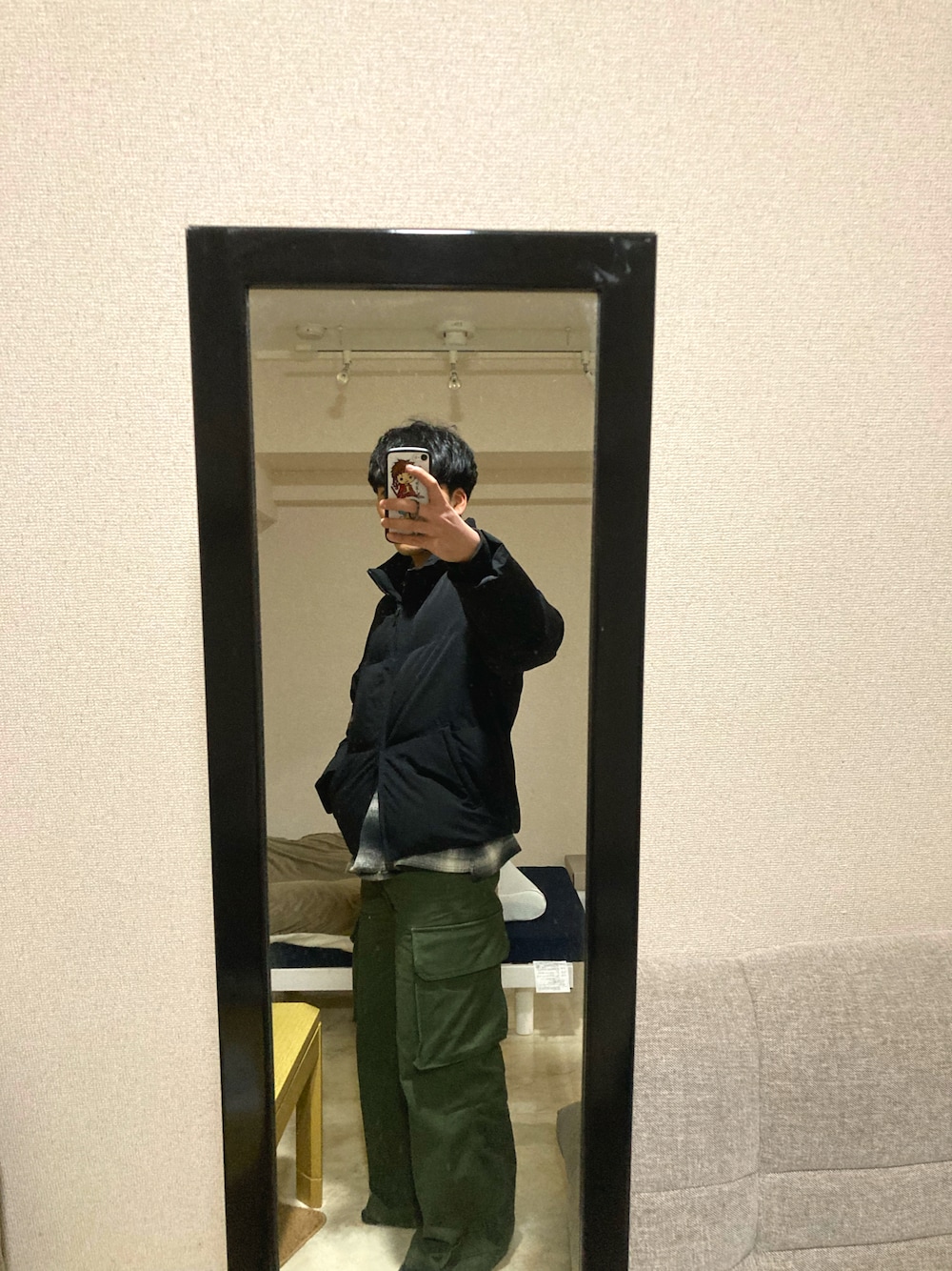 グリーン系のカーゴパンツ、ブラック系のダウンジャケット/コート、ブラック系のシャツ/ブラウスを着用したメンズの春コーディネートの1枚目の写真