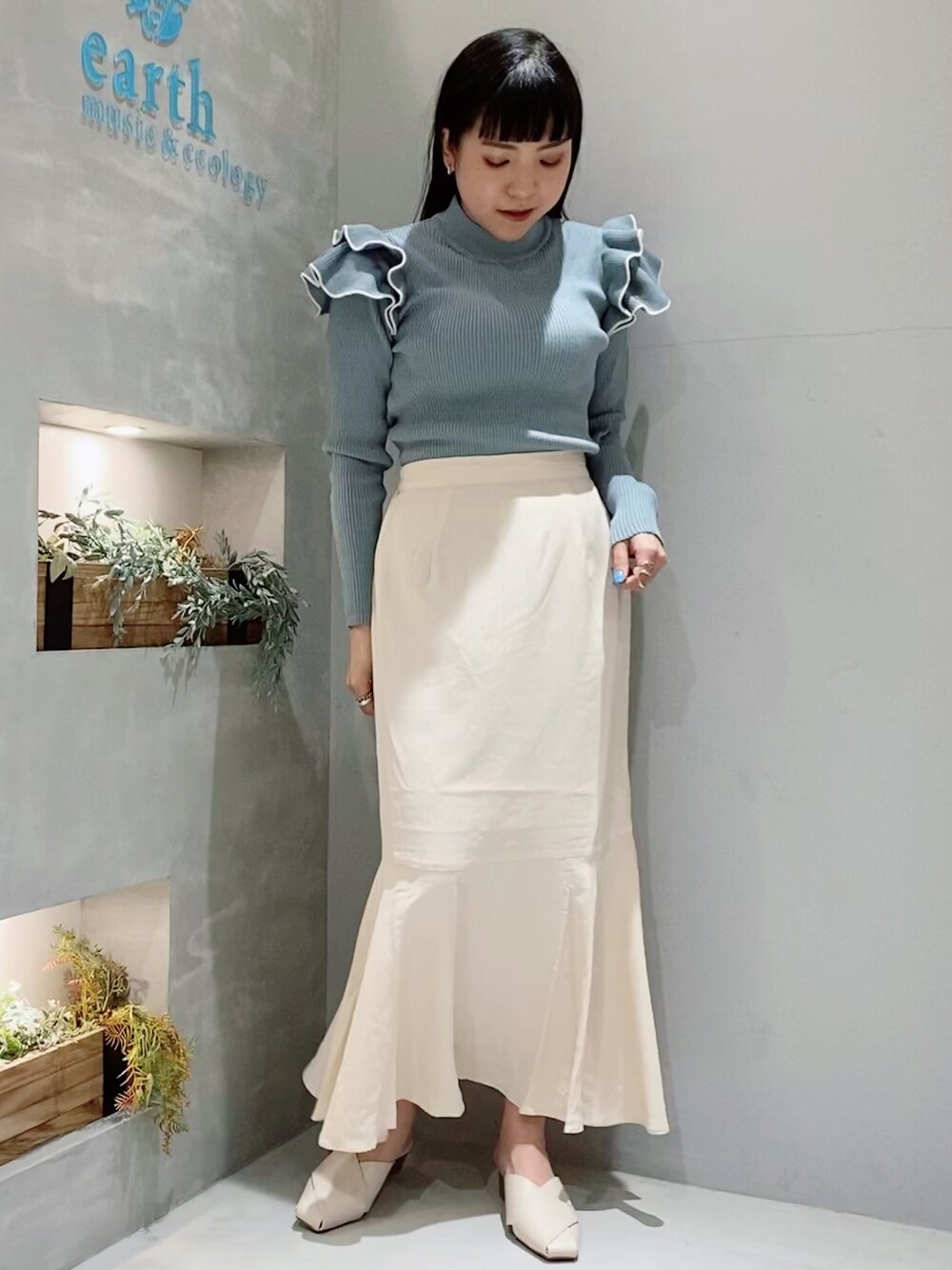 ベージュ系のスカート、ブルー系のニット/セーター、ホワイト系のサンダルを着用したレディースの春コーディネートの1枚目の写真