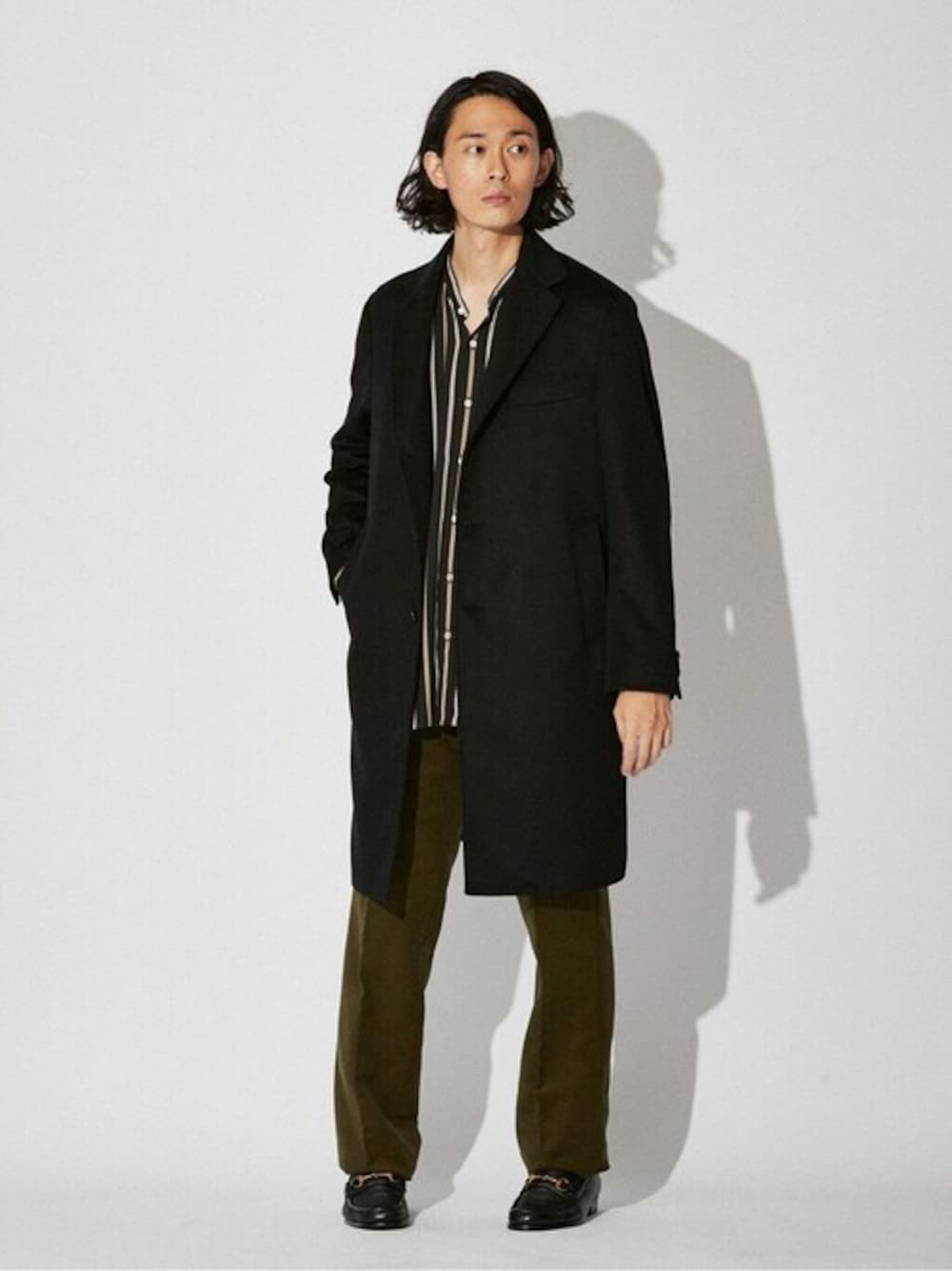 ブラック系のチェスターコート、ブラック系のシャツ/ブラウス、グリーン系のその他パンツを着用したメンズの秋コーディネートの1枚目の写真