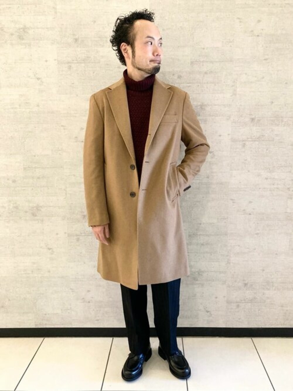 ベージュ系のチェスターコート、ブラック系のその他パンツ、ブラック系のブーツを着用したメンズの秋コーディネートの1枚目の写真