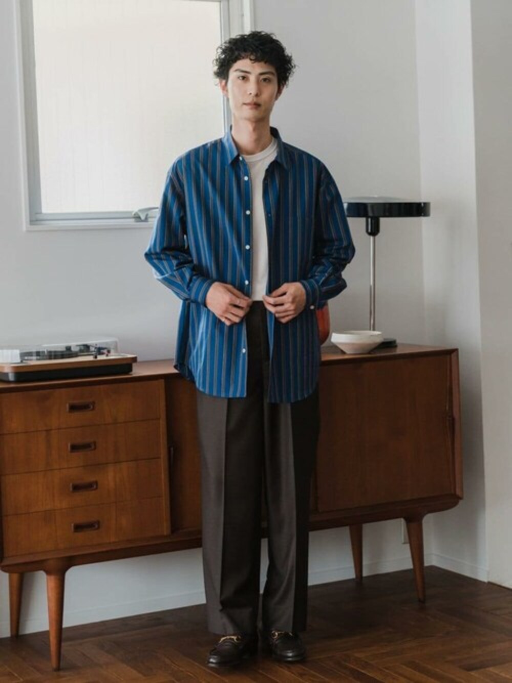 ブルー系のシャツ/ブラウス、ホワイト系のTシャツ/カットソー、ブラウン系のスラックスを着用したメンズの秋コーディネートの1枚目の写真