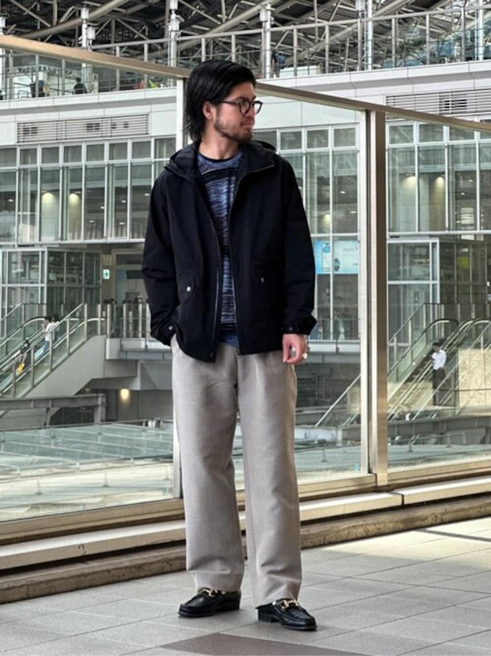 ブラック系のブルゾン、ブラック系のニット/セーター、ベージュ系のスラックスを着用したメンズの秋コーディネートの1枚目の写真