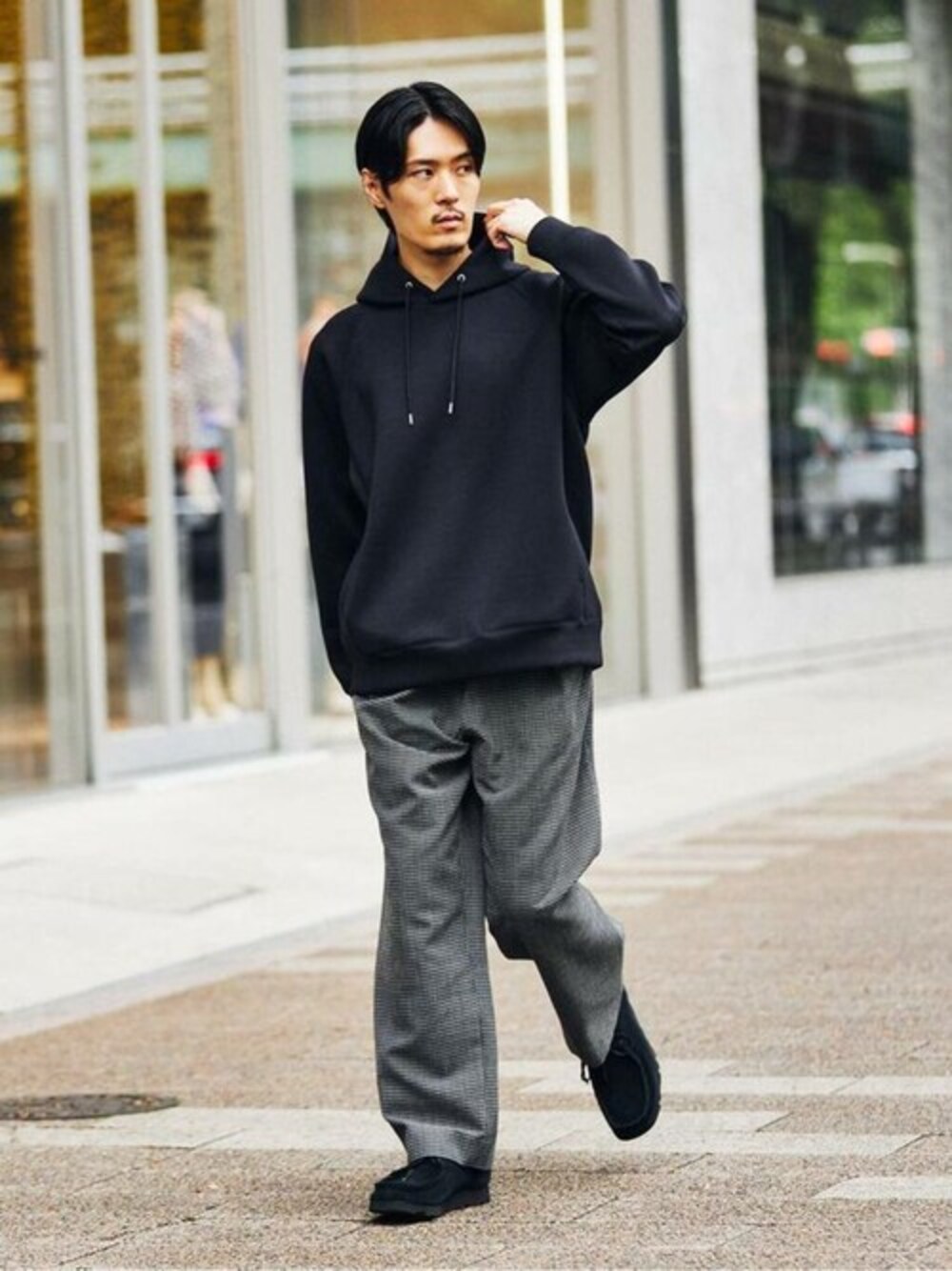 ブラック系のパーカー、ブラック系のスラックス、ブラック系のブーツを着用したメンズの秋コーディネートの1枚目の写真