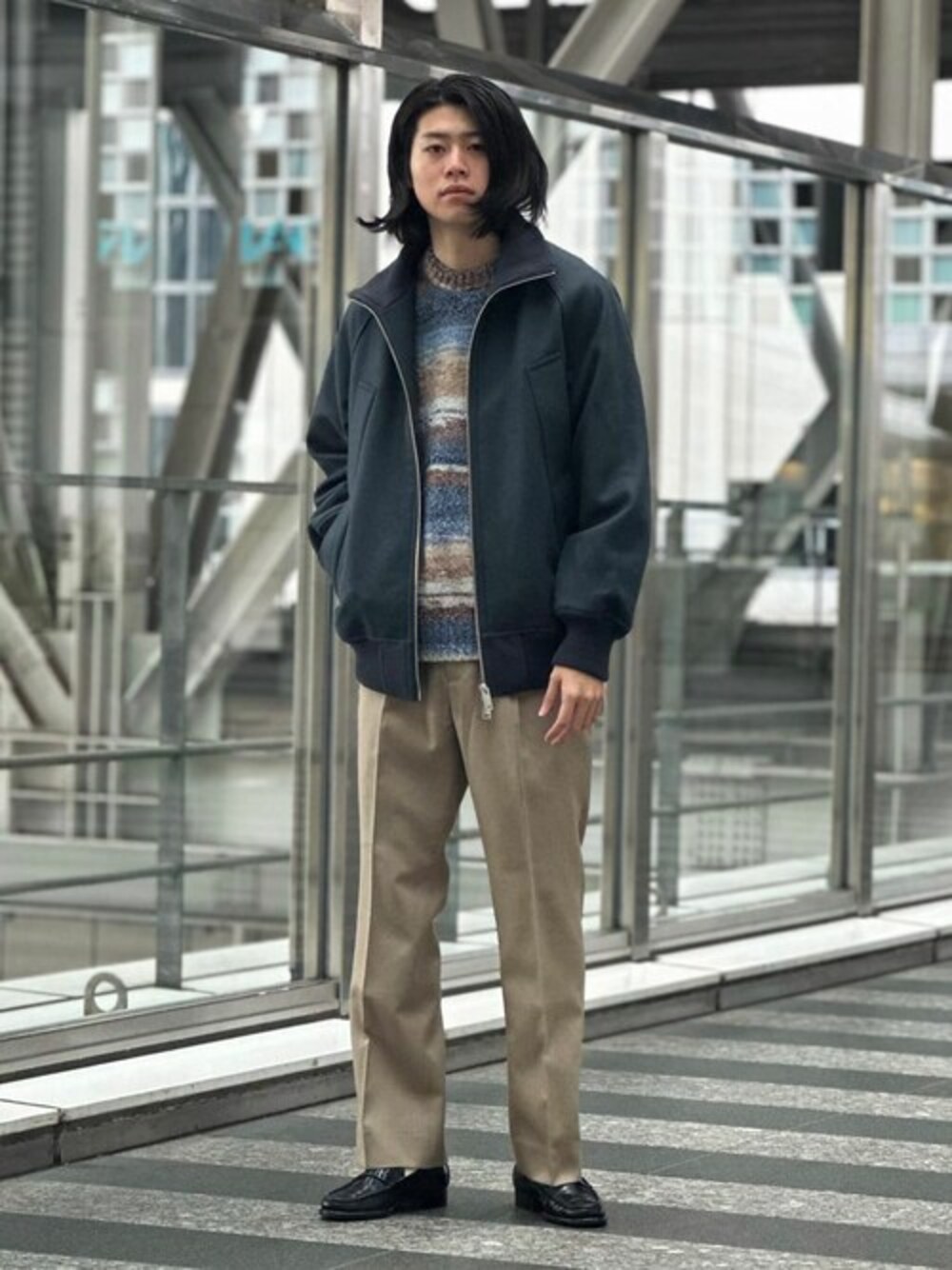 グレー系のブルゾン、レッド系のニット/セーター、ベージュ系のスラックスを着用したメンズの秋コーディネートの1枚目の写真