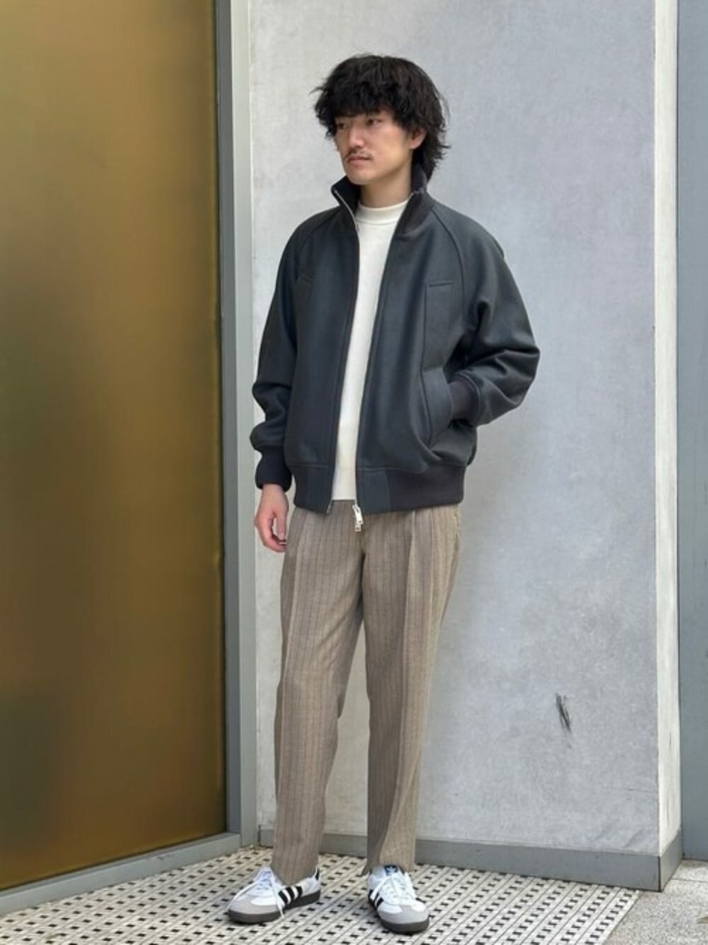 グレー系のブルゾン、ホワイト系のニット/セーター、ベージュ系のスラックスを着用したメンズの秋コーディネートの1枚目の写真
