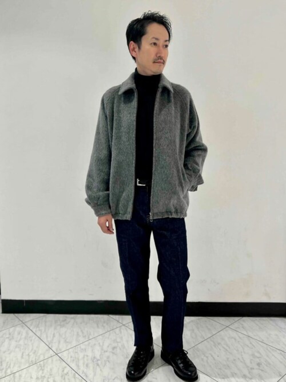 グレー系のその他アウター、ブラック系のニット/セーター、ブルー系のデニムパンツを着用したメンズの秋コーディネートの1枚目の写真