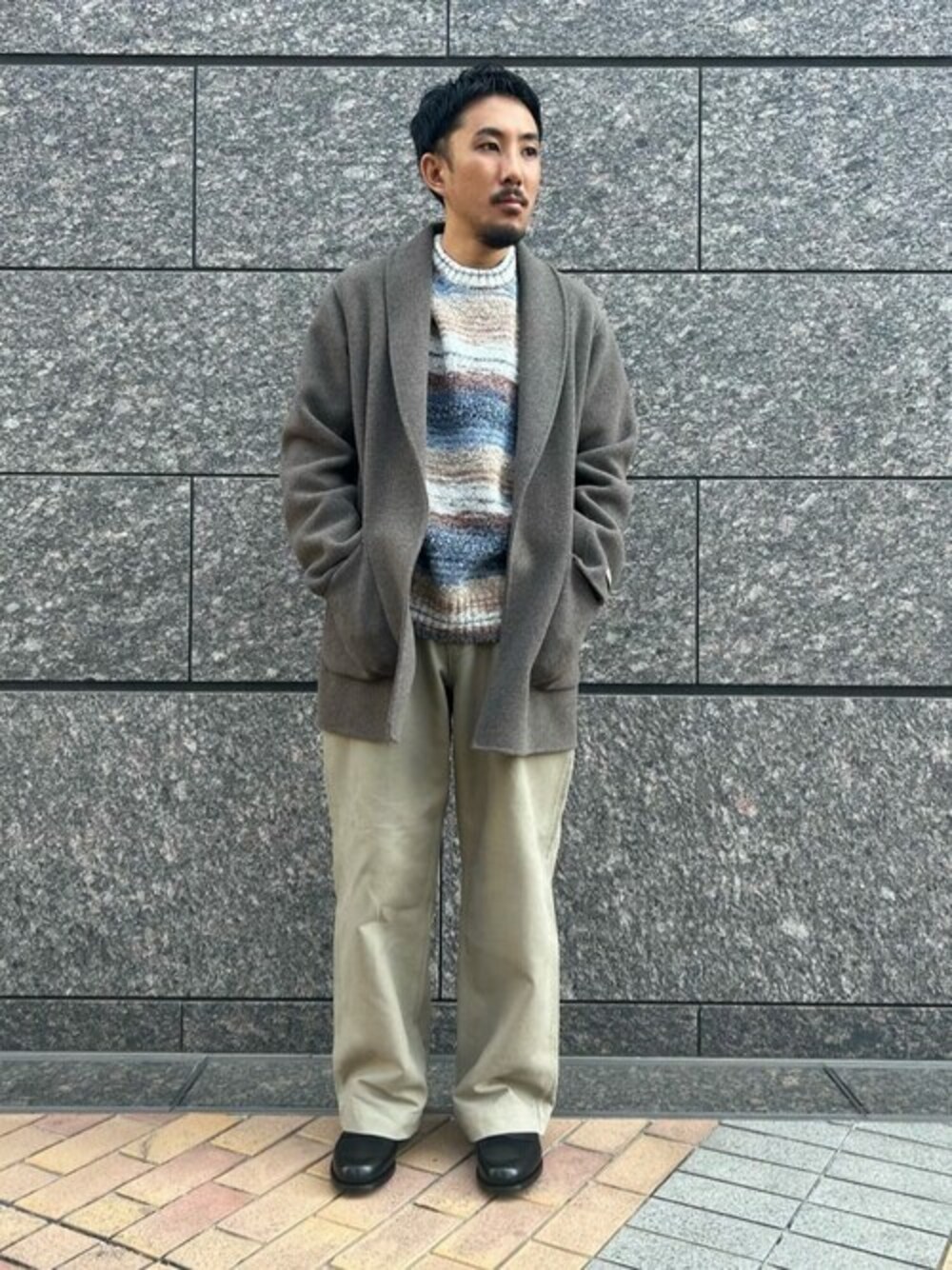 ブラウン系のチェスターコート、ブルー系のニット/セーター、ベージュ系のその他パンツを着用したメンズの秋コーディネートの1枚目の写真
