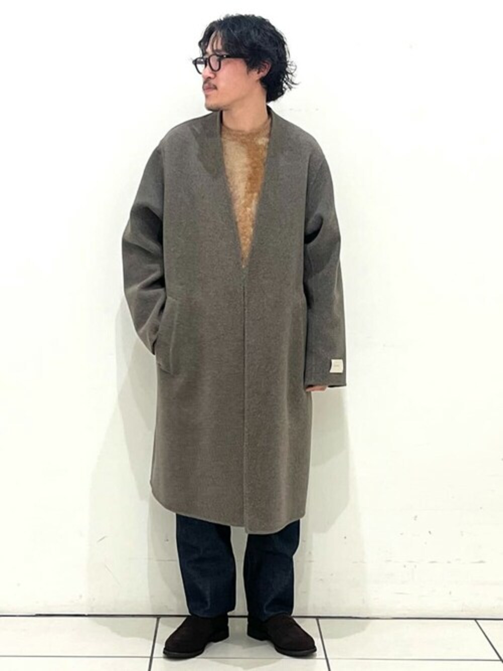 ブラウン系のノーカラーコート、ブラウン系のニット/セーター、ブラウン系のローファーを着用したメンズの秋コーディネートの1枚目の写真