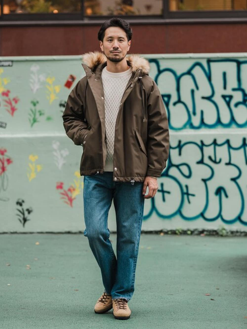 グリーン系のダウンジャケット/コート、ホワイト系のニット/セーター、ブルー系のデニムパンツを着用したメンズの冬コーディネートの1枚目の写真