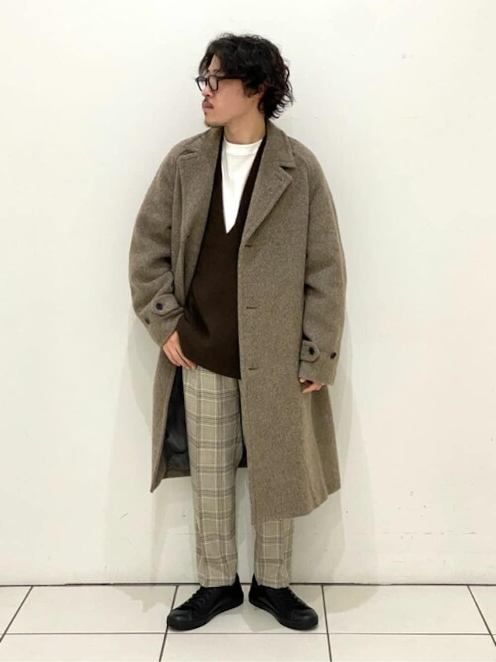 ベージュ系のチェスターコート、ブラウン系のニット/セーター、ベージュ系のスラックスを着用したメンズの冬コーディネートの1枚目の写真