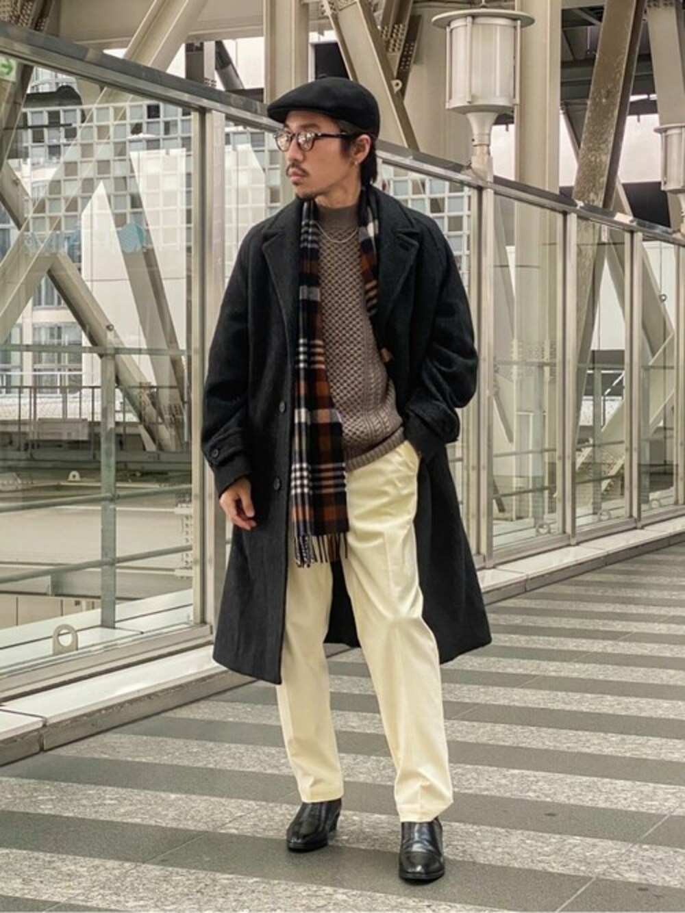 グレー系のチェスターコート、ベージュ系のニット/セーター、ホワイト系のスラックスを着用したメンズの冬コーディネートの1枚目の写真