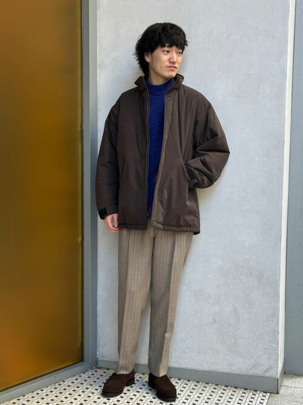 ブラウン系のその他アウター、ブルー系のニット/セーター、ベージュ系のスラックスを着用したメンズの冬コーディネートの1枚目の写真
