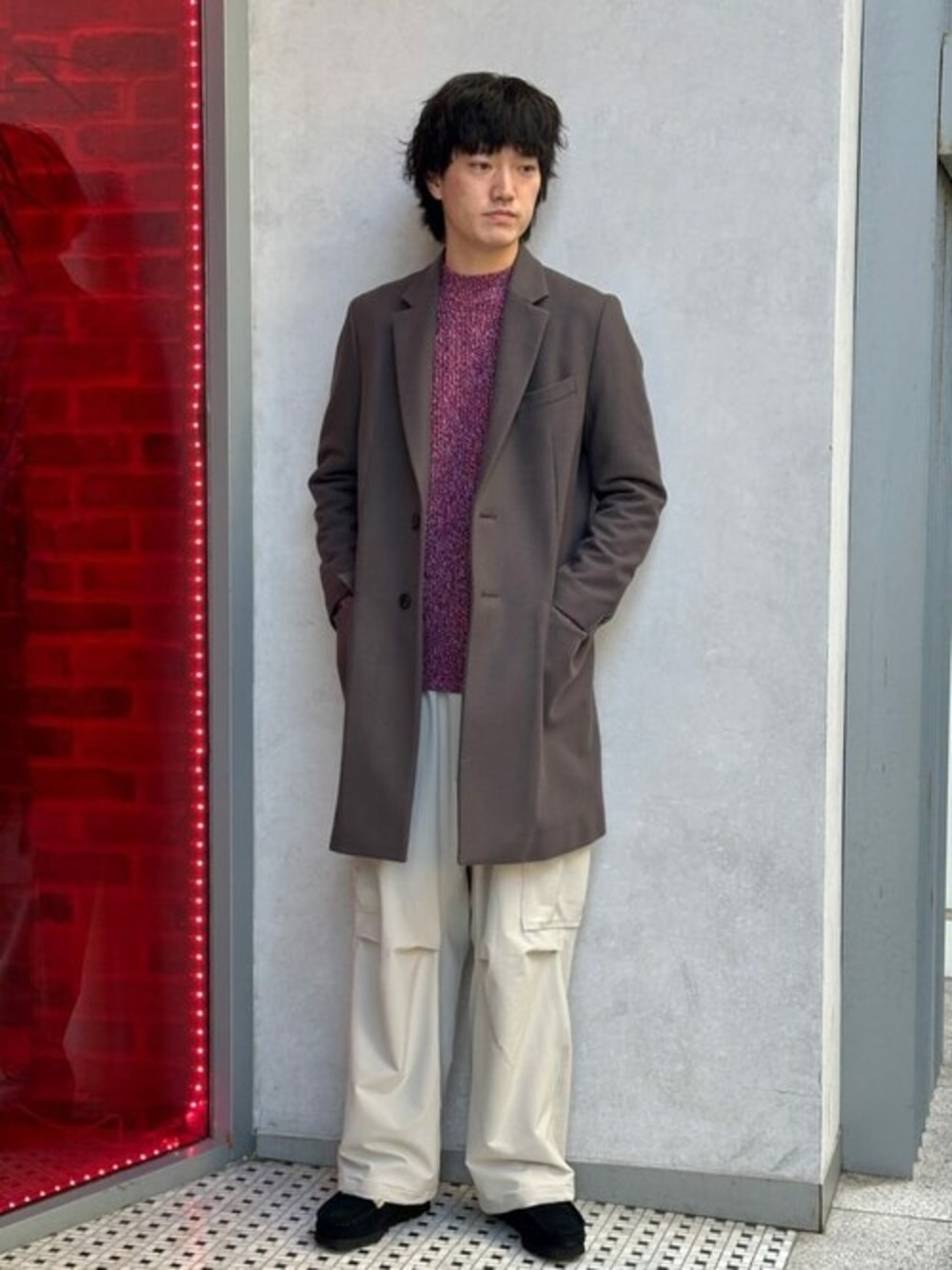 レッド系のニット/セーター、グレー系のチェスターコート、ホワイト系のカーゴパンツを着用したメンズの冬コーディネートの1枚目の写真