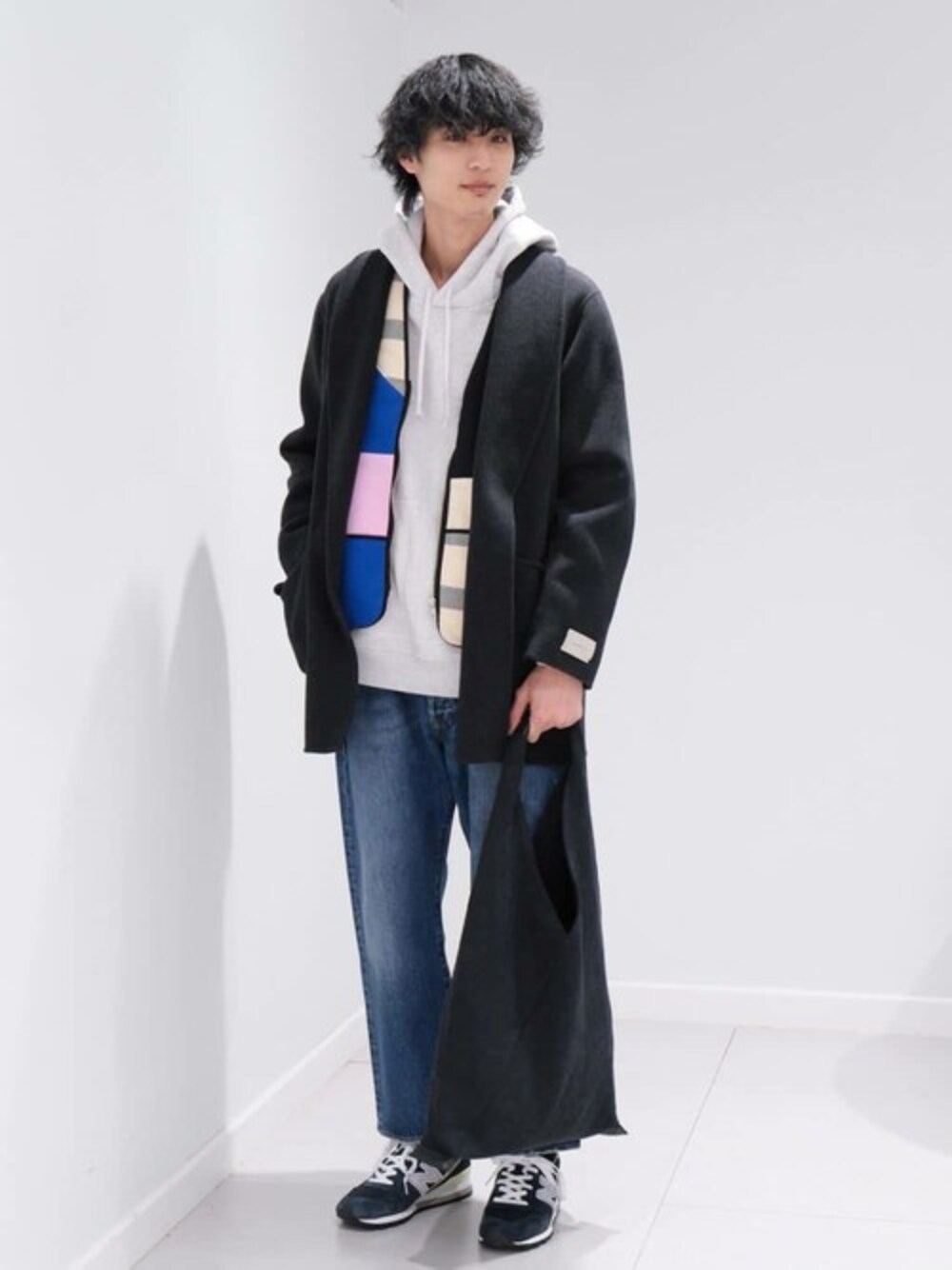 グレー系のチェスターコート、ブルー系のデニムパンツ、ブルー系のスニーカーを着用したメンズの冬コーディネートの1枚目の写真