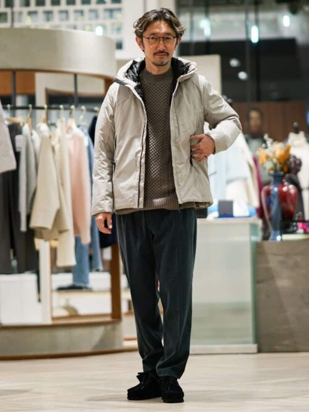 ベージュ系のダウンジャケット/コート、ベージュ系のニット/セーター、グレー系のスラックスを着用したメンズの冬コーディネートの1枚目の写真