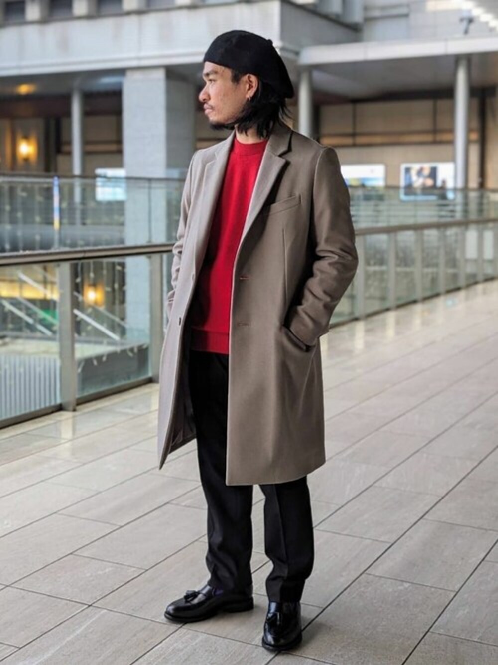 ベージュ系のチェスターコート、レッド系のニット/セーター、ブラック系のスラックスを着用したメンズの冬コーディネートの1枚目の写真