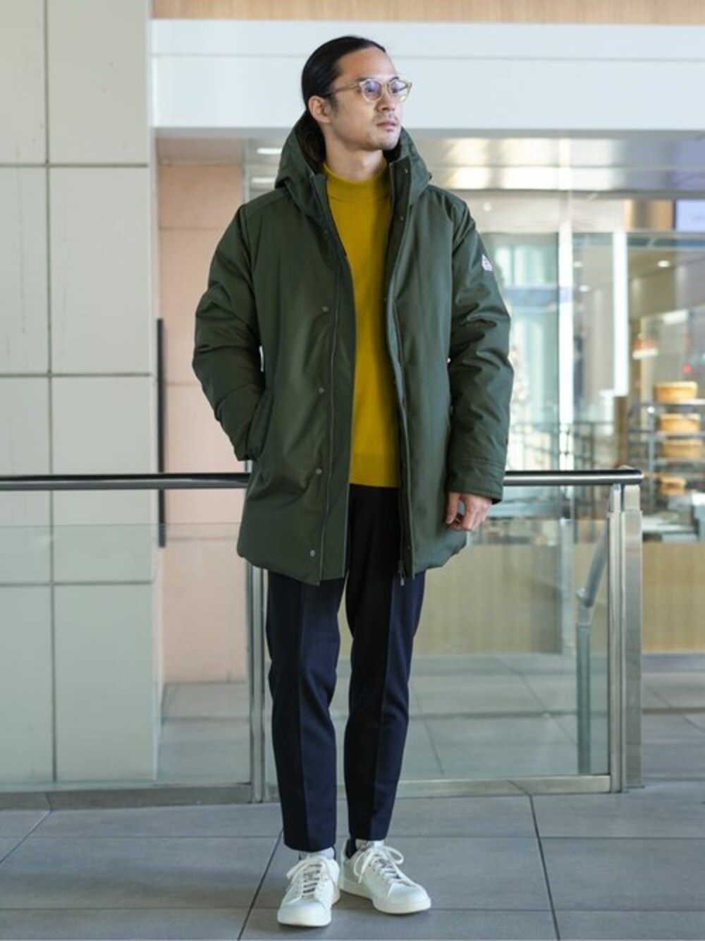 グリーン系のダウンジャケット/コート、イエロー系のニット/セーター、ブラック系のスラックスを着用したメンズの冬コーディネートの1枚目の写真