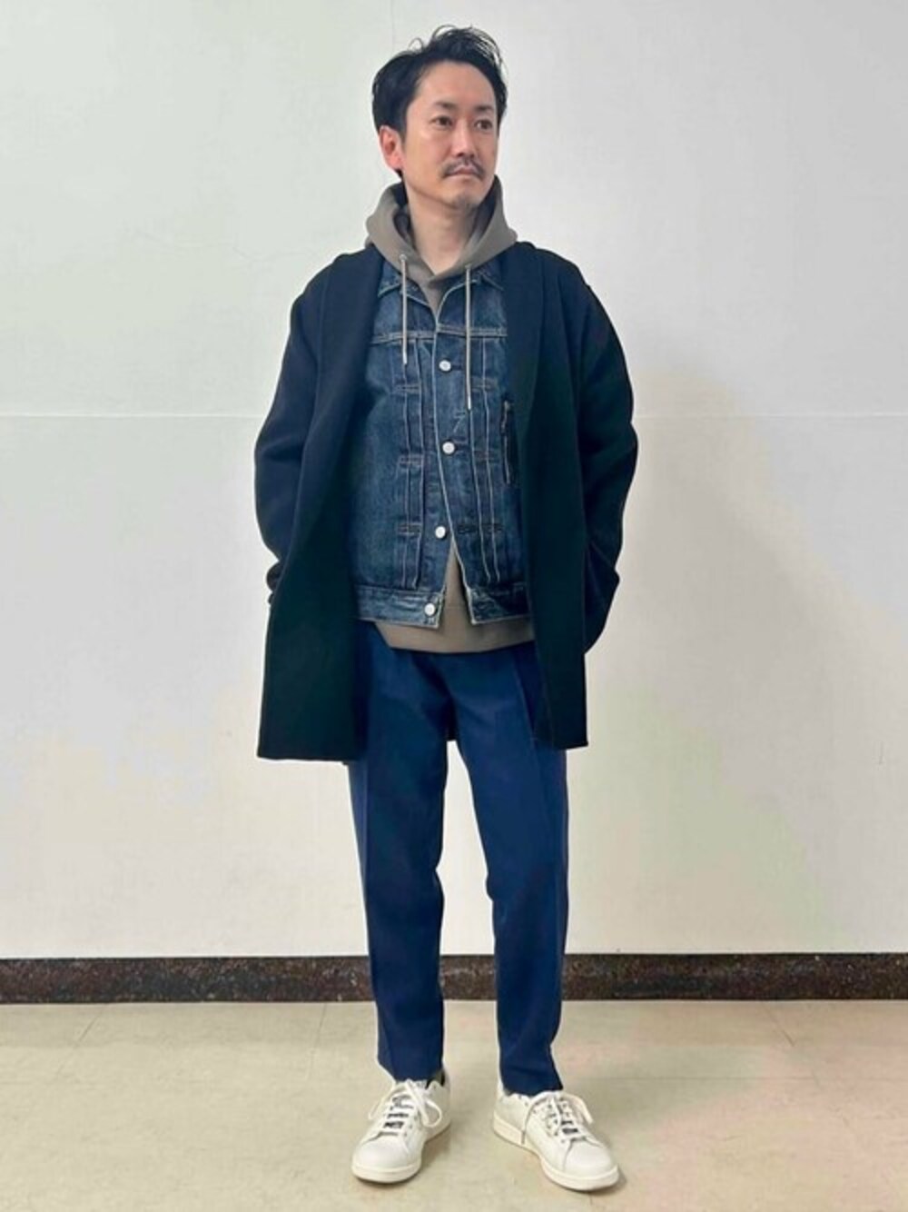 ブルー系のチェスターコート、ブルー系のデニムジャケット、ブラウン系のパーカーを着用したメンズの冬コーディネートの1枚目の写真