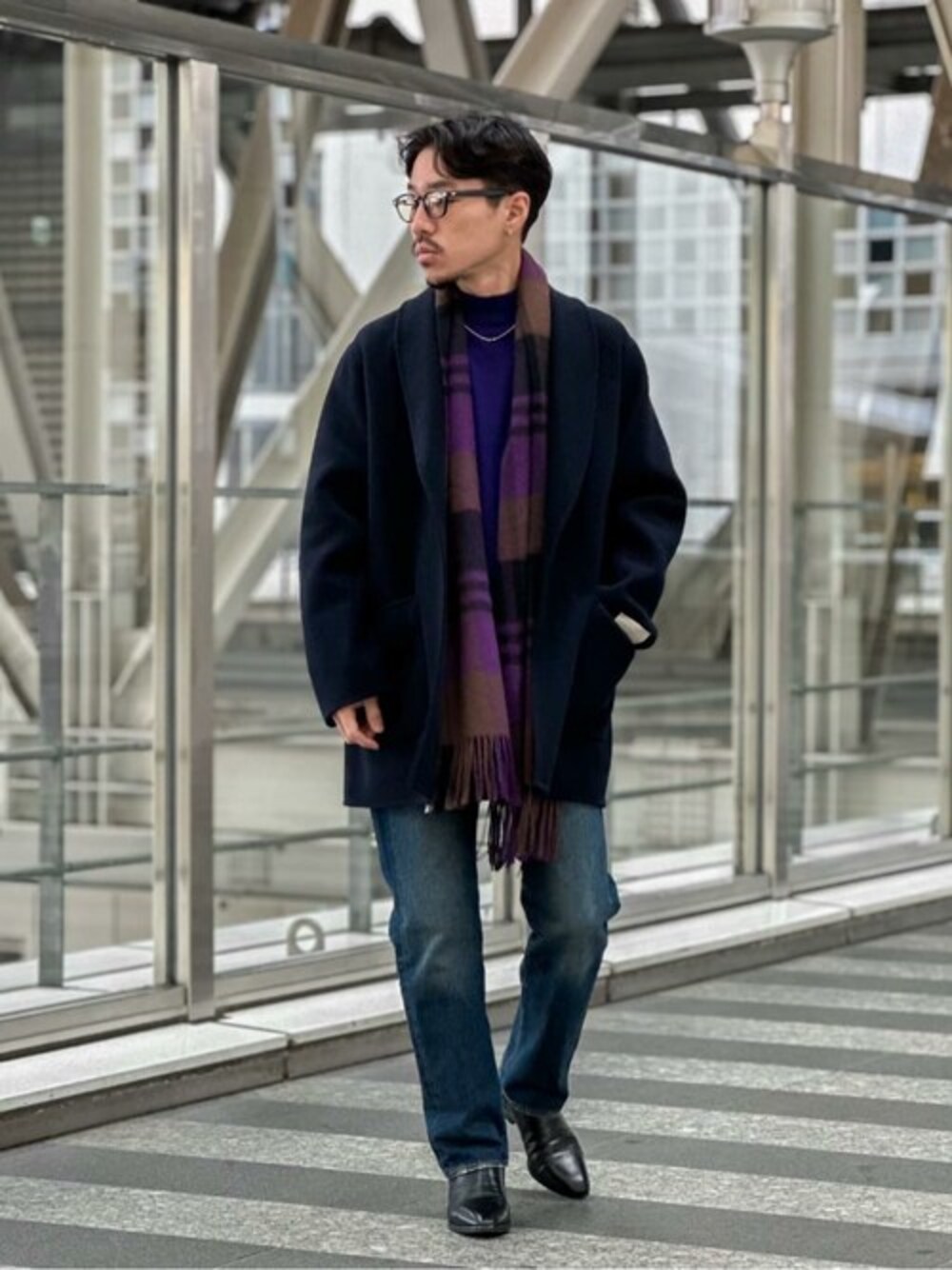 ブルー系のチェスターコート、パープル系のニット/セーター、ブルー系のデニムパンツを着用したメンズの冬コーディネートの1枚目の写真