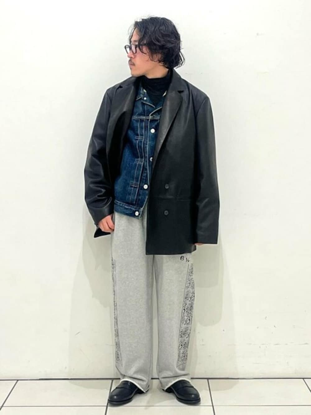 ブラック系のテーラードジャケット、ブルー系のデニムジャケット、グレー系のスウェットパンツを着用したメンズの冬コーディネートの1枚目の写真