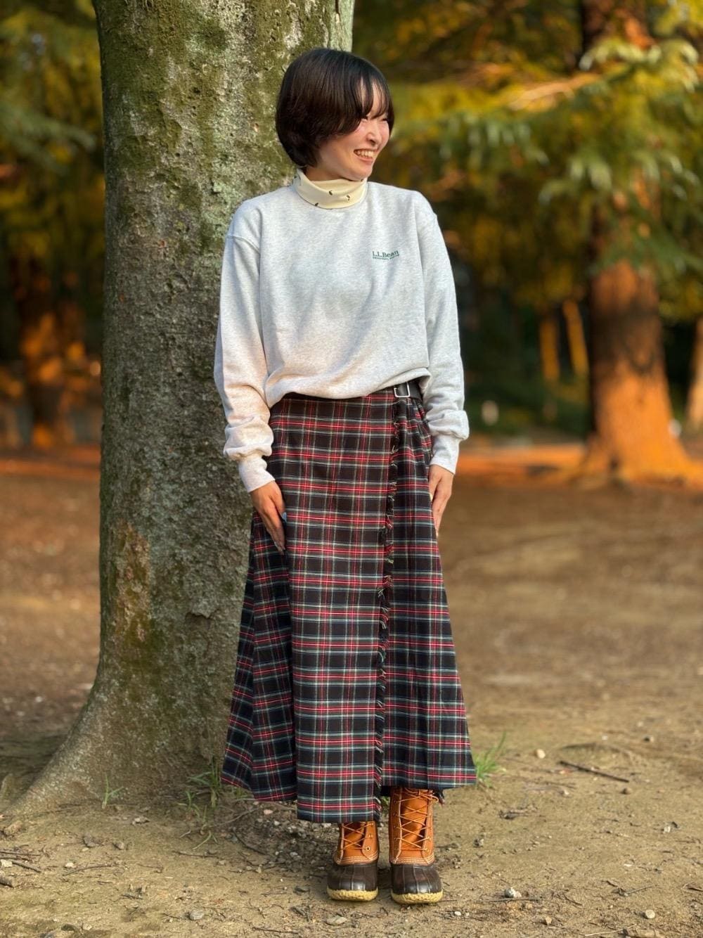 ブラウン系のブーツ、グレー系のスウェット、ブラック系のスカートを着用したレディースの秋コーディネートの1枚目の写真